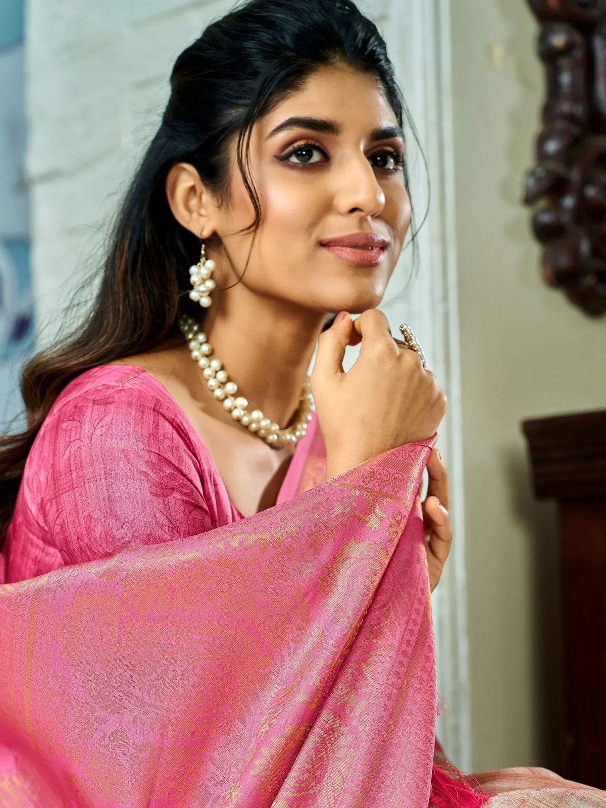 Elegant woman in pink ethnic saree with gold embroidery and pearl jewelry