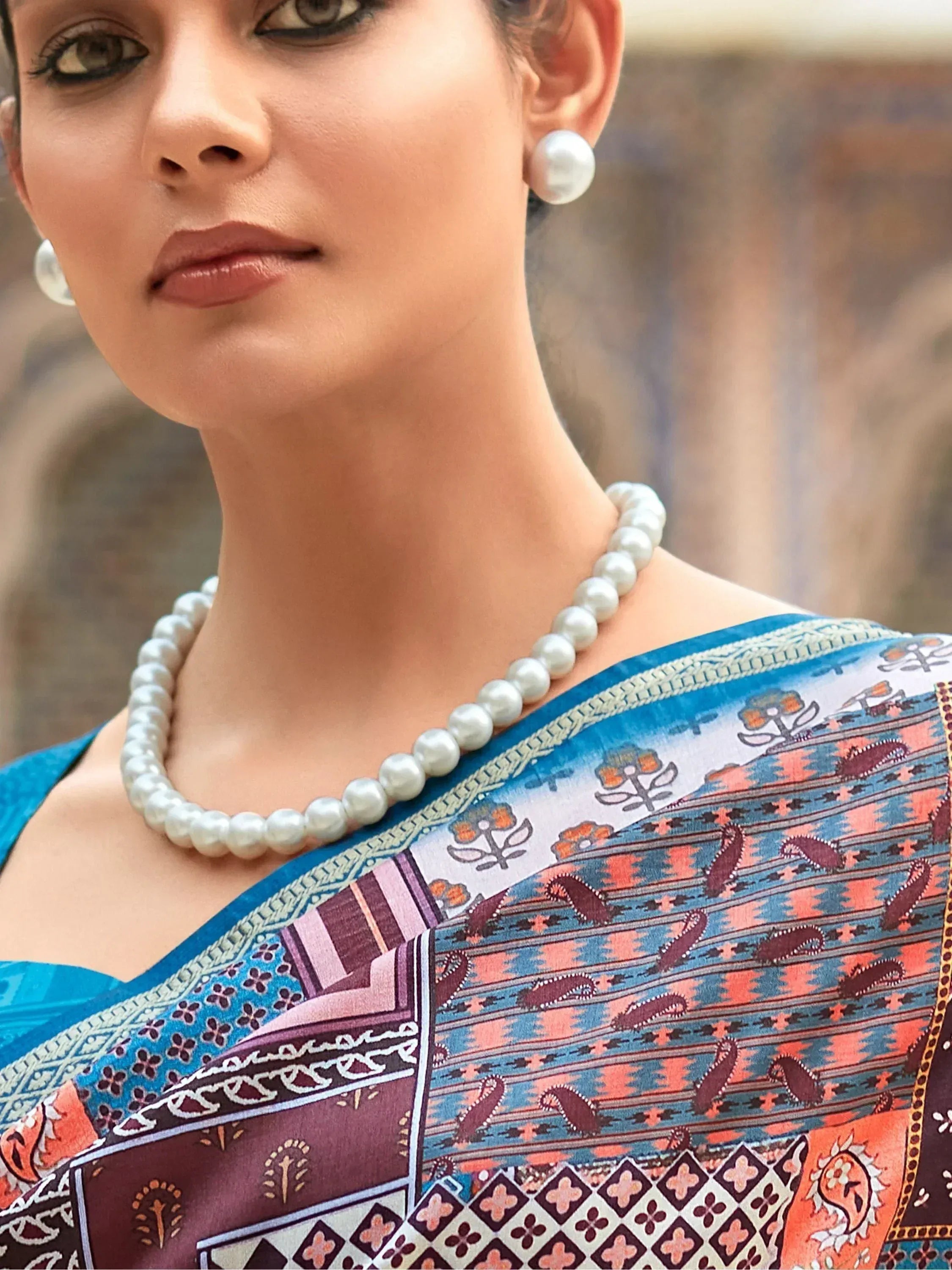 Woman in printed ethnic saree with pearl necklace and earrings, stylish Indian wear