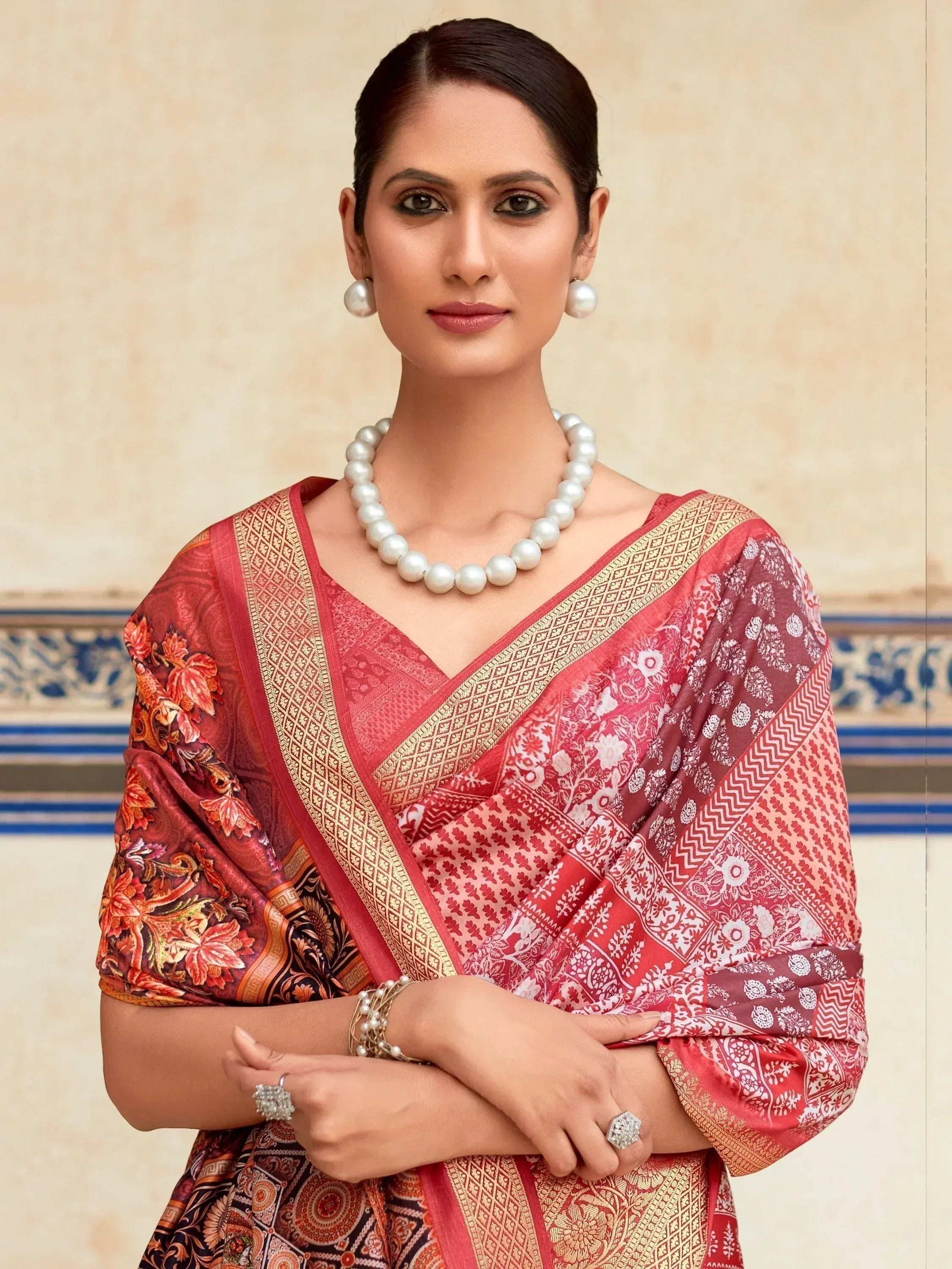 Woman in red printed saree with gold border, pearl jewelry, ethnic Indian wear