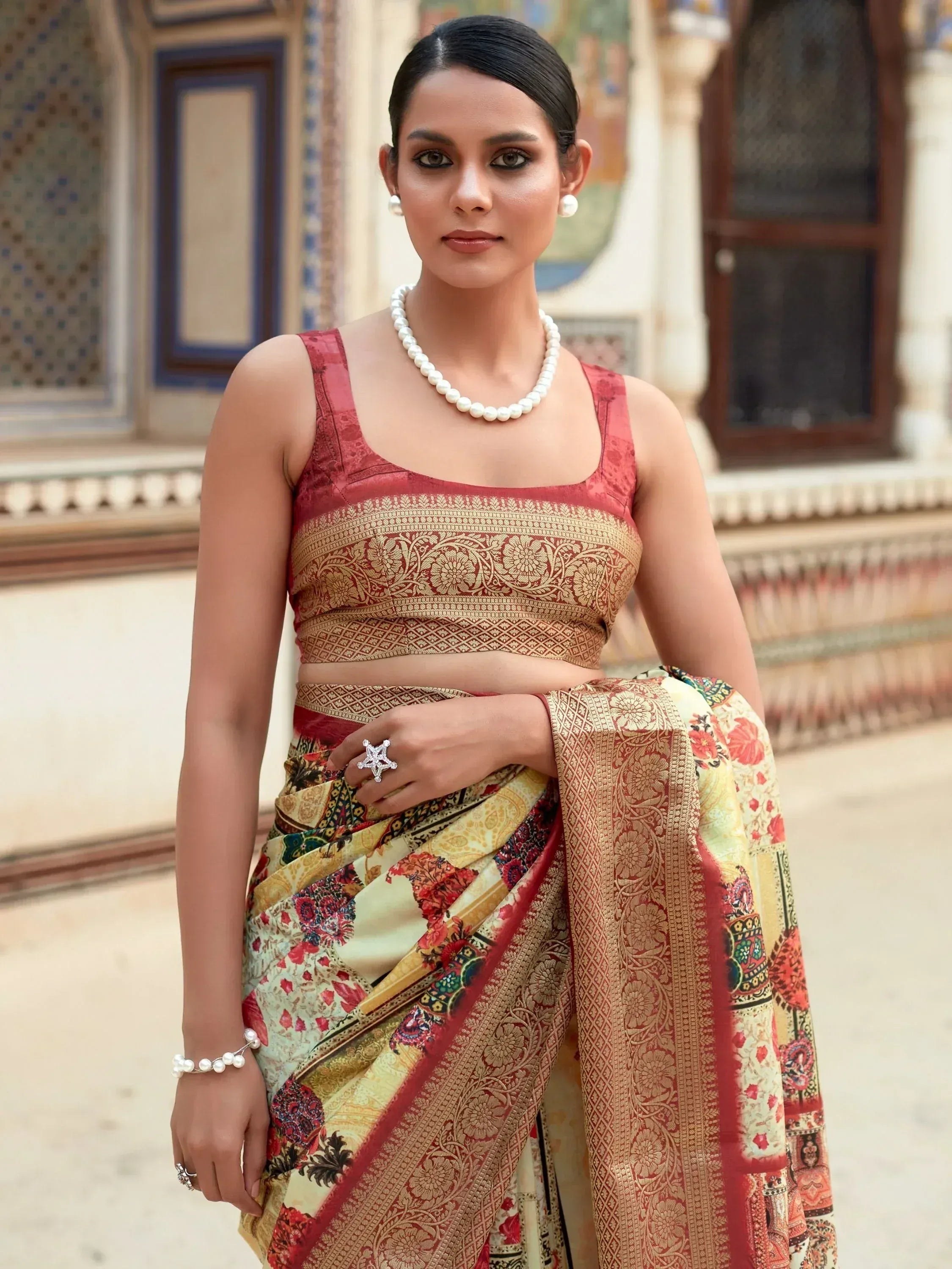 Woman in elegant Indian saree with floral print and gold border, paired with pearl jewelry, traditional ethnic wear