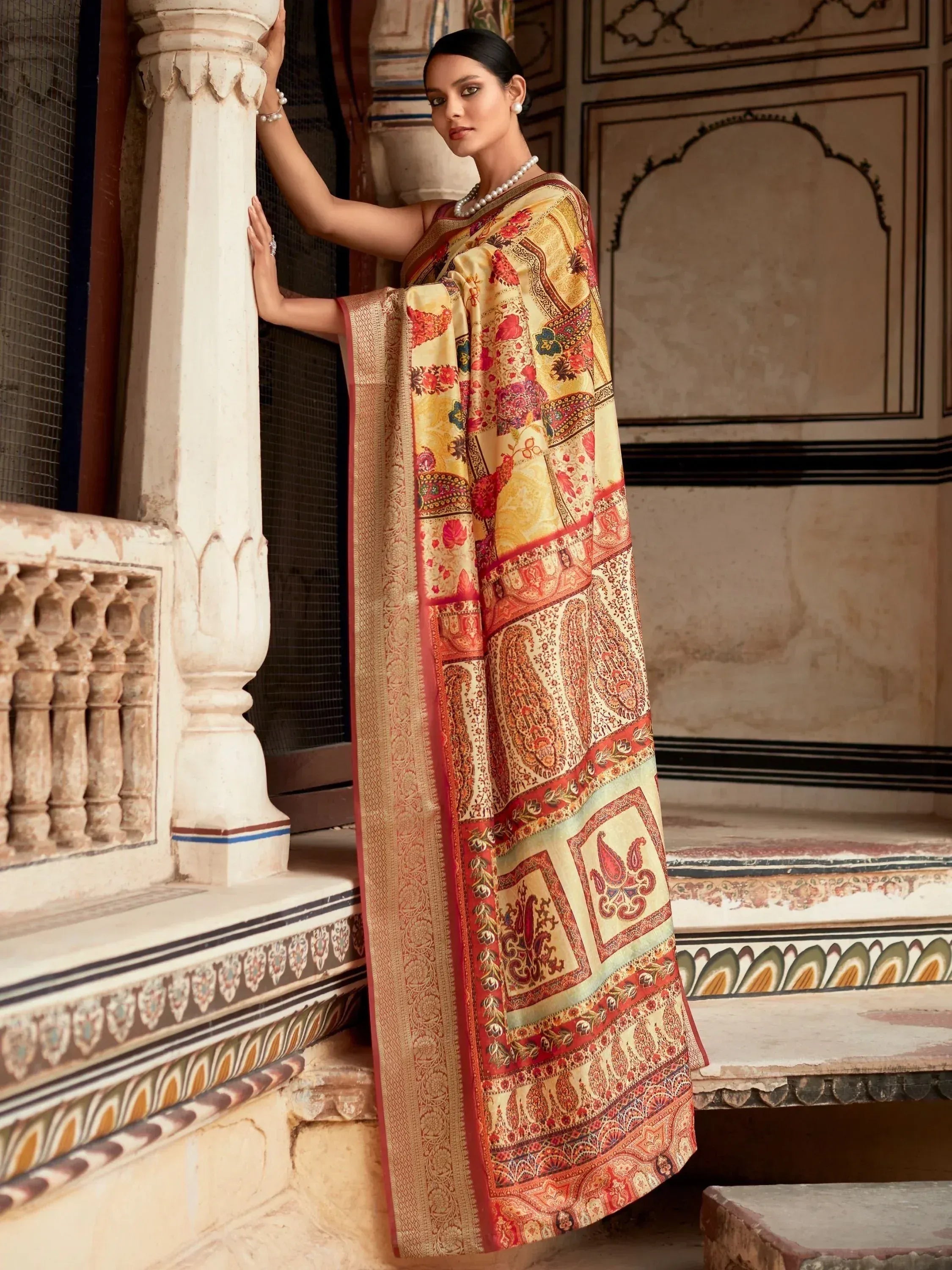 Elegant woman in floral and paisley printed saree, traditional Indian ethnic wear, standing by ornate pillar