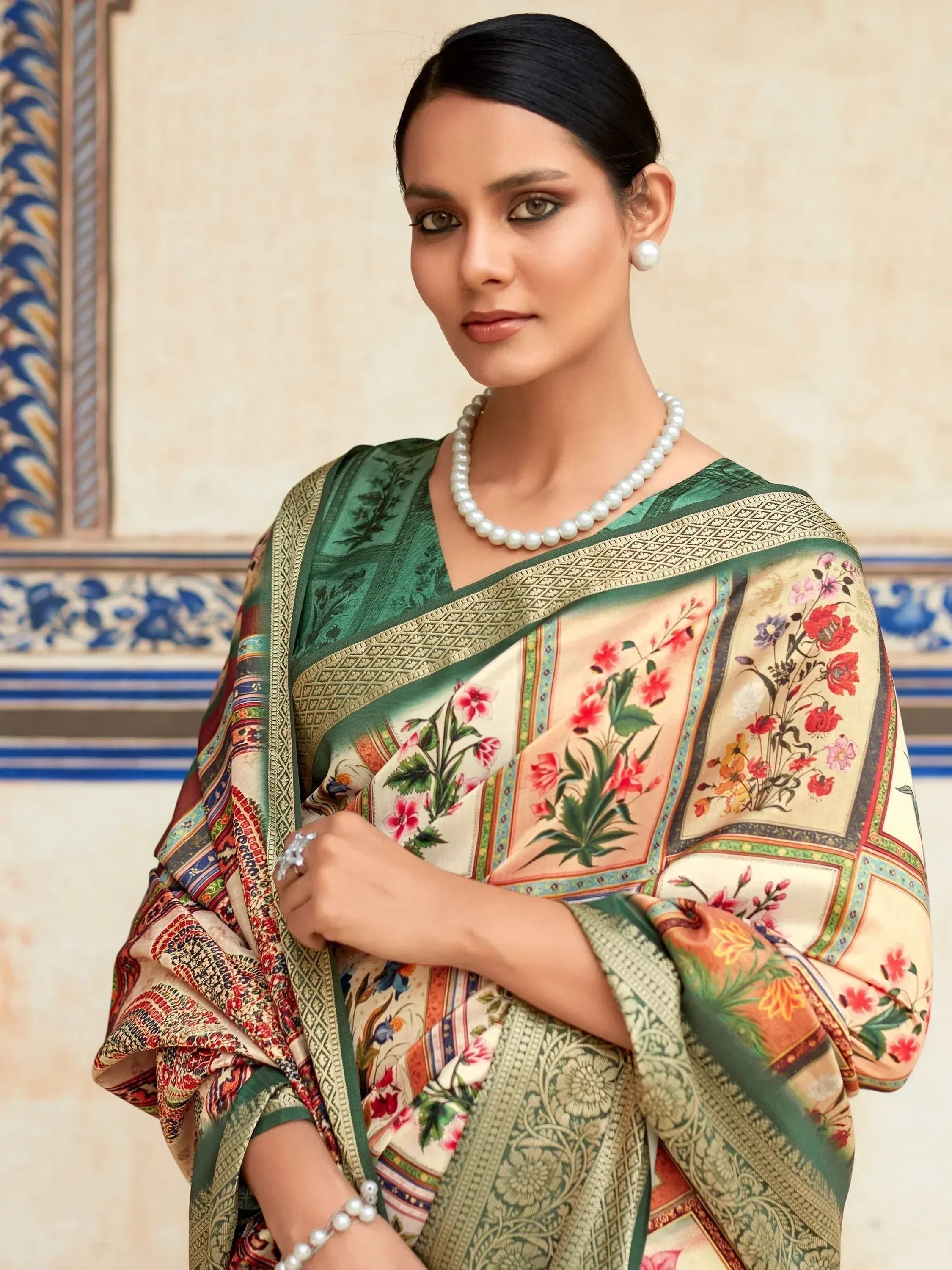 Woman in elegant floral print saree with green border, styled with pearl jewelry for ethnic occasions