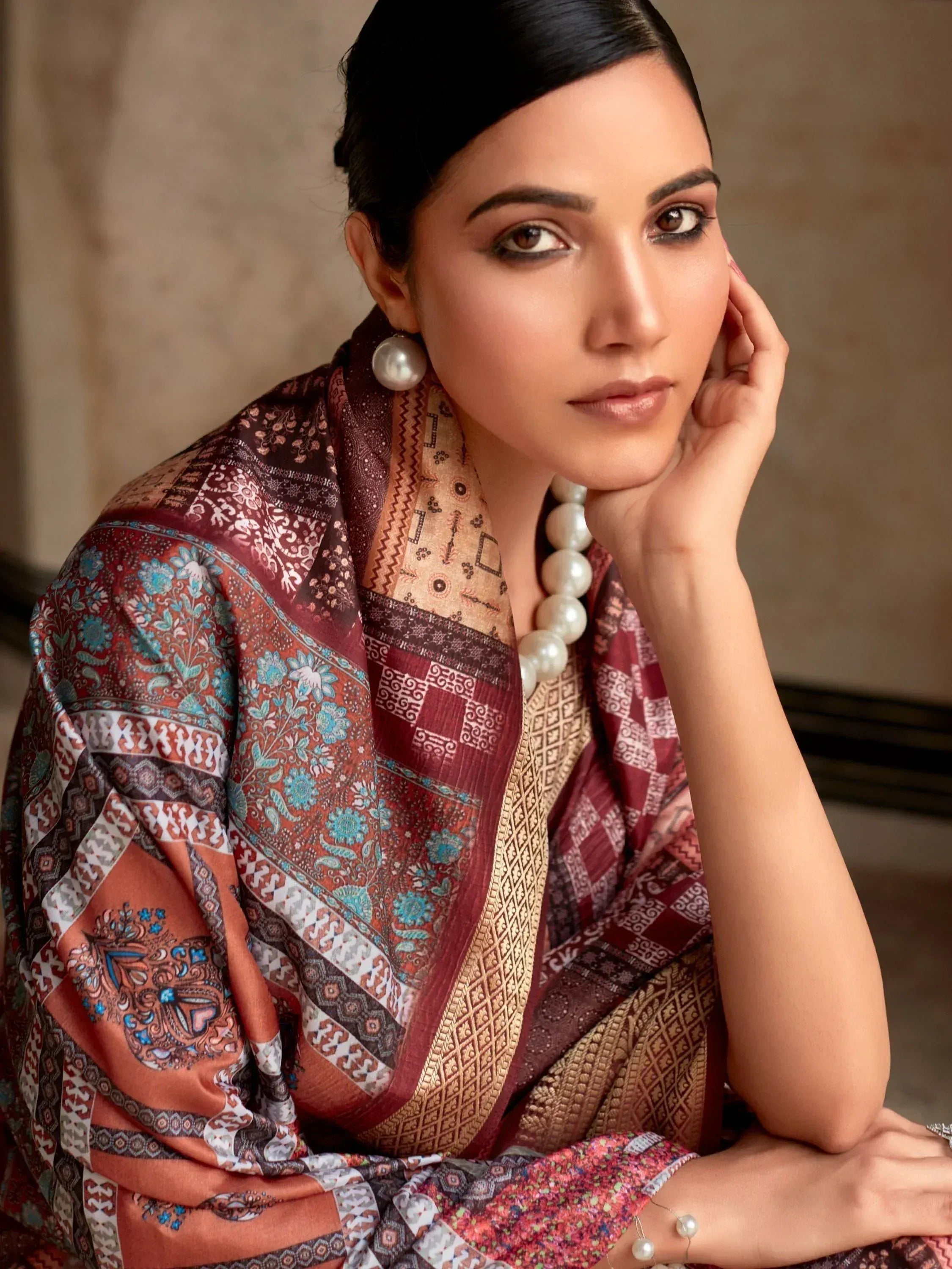 Woman in elegant ethnic saree with intricate paisley and geometric print, paired with pearl jewelry.