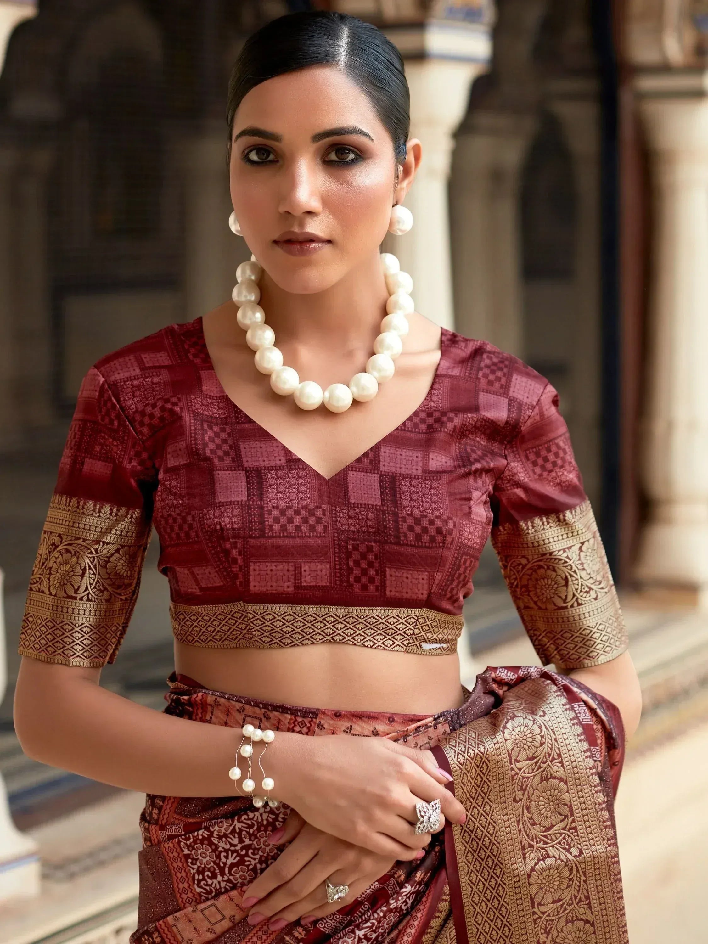 Woman in maroon ethnic saree with gold border and pearl jewelry, traditional Indian wear