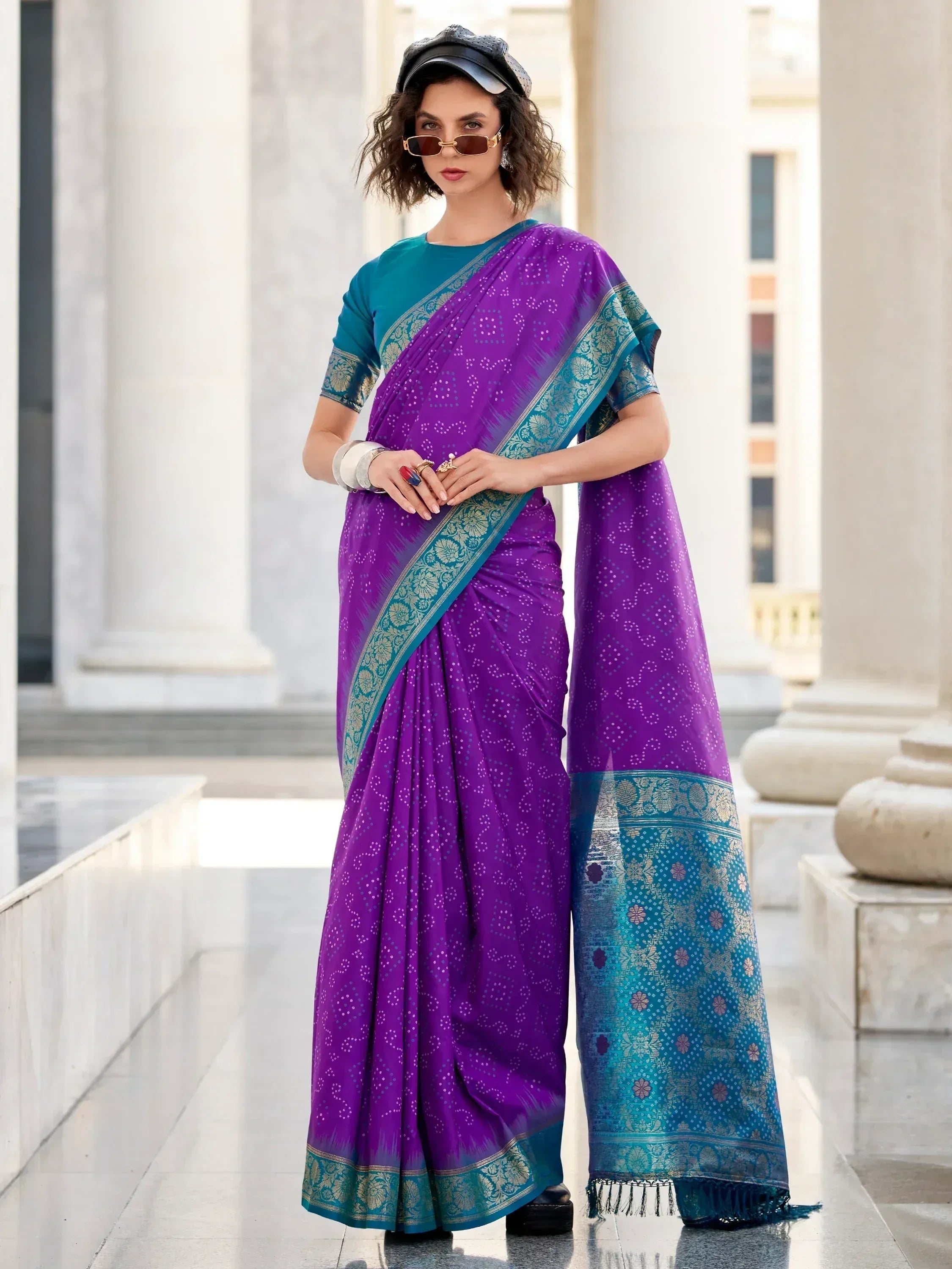 Purple and teal designer saree with floral border, styled with sunglasses and cap for modern ethnic look