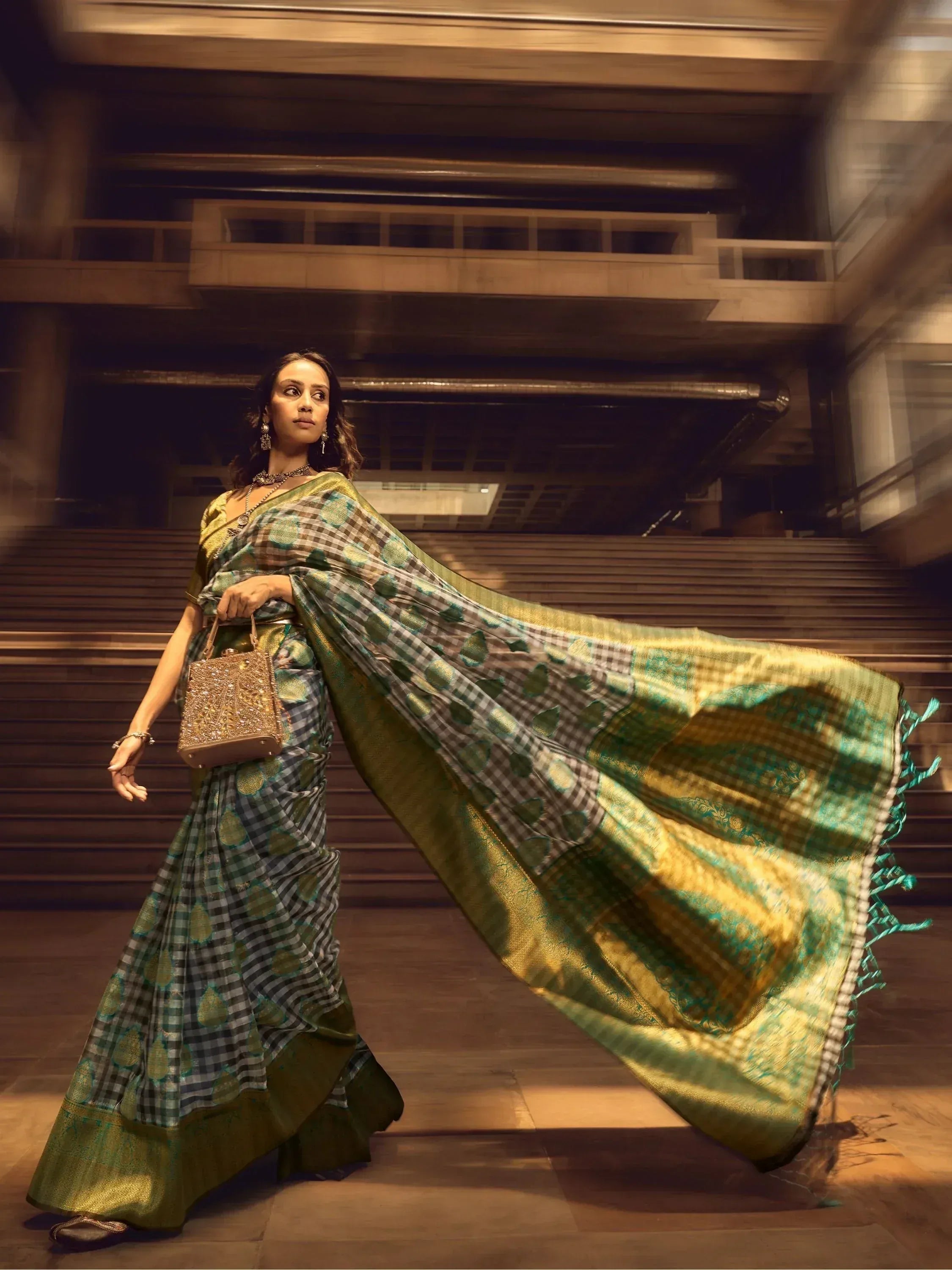 Woman in elegant green and gold checkered saree with flowing pallu, perfect for Indian ethnic occasions