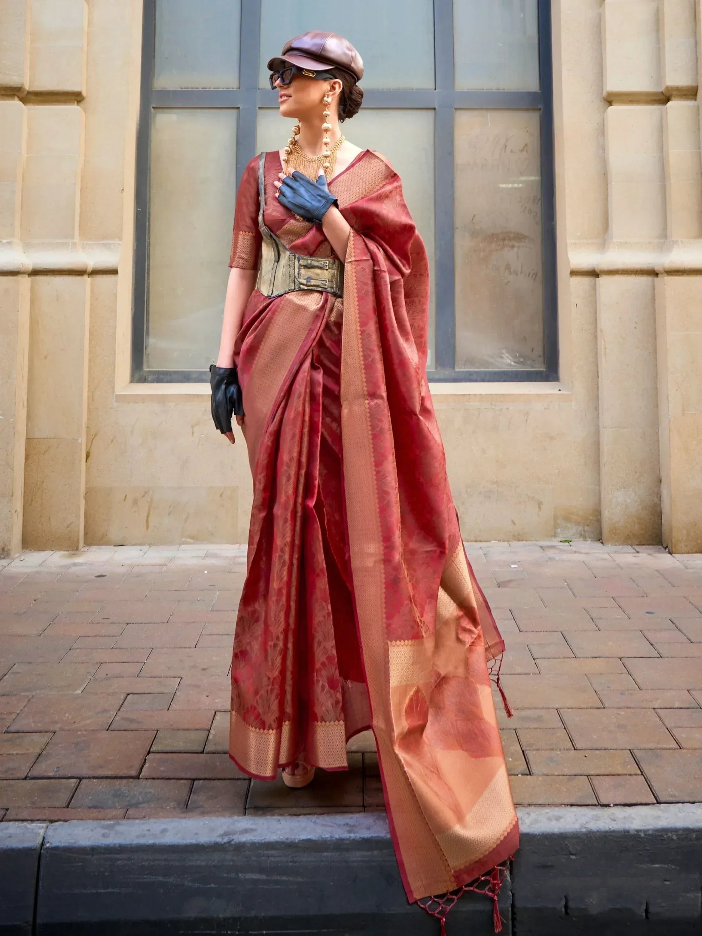 Woman in elegant red and gold designer saree with corset, cap, and gloves, styled for ethnic fashion
