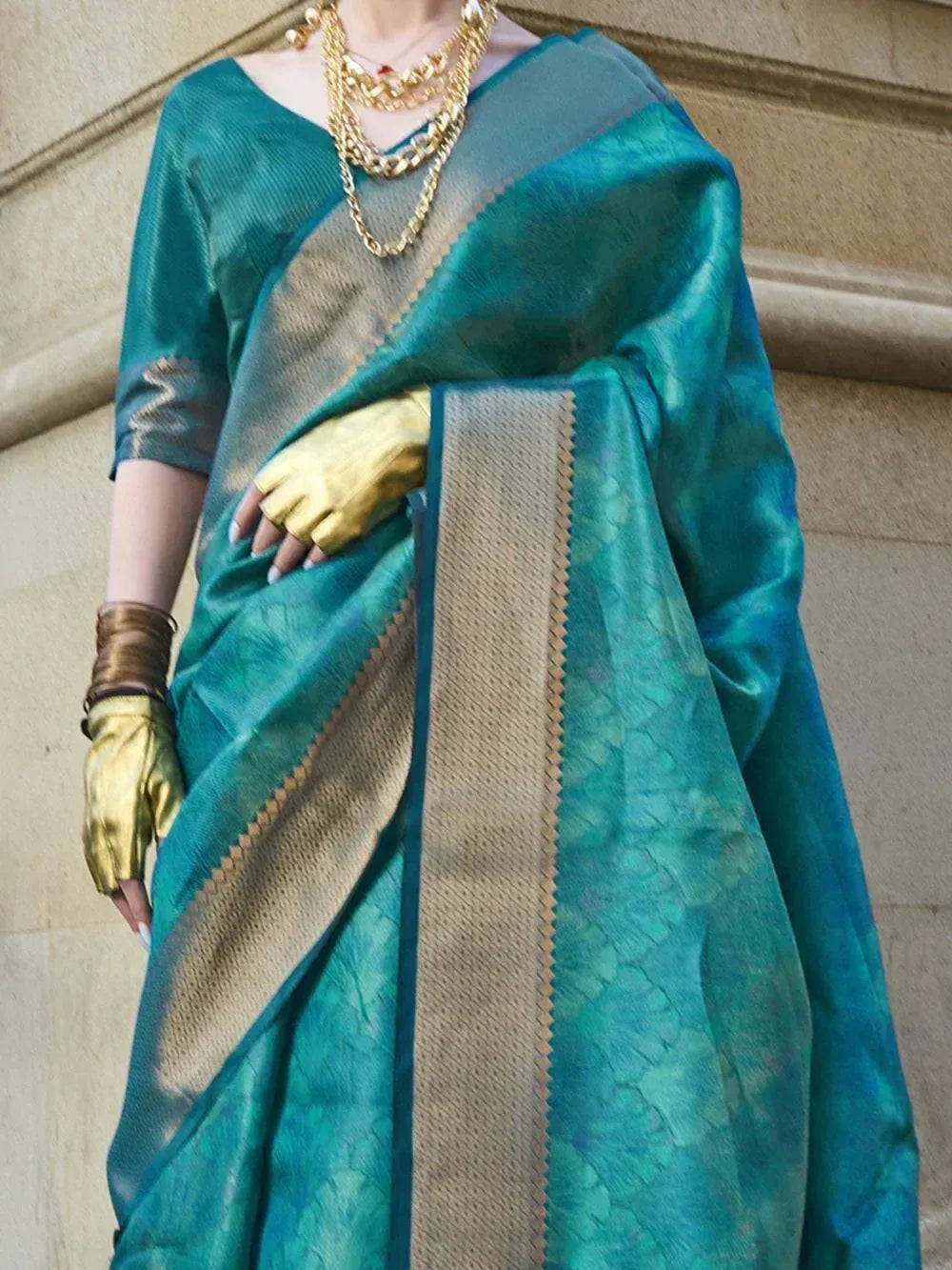 Teal silk saree with gold border, paired with matching blouse and gold jewelry for ethnic wear