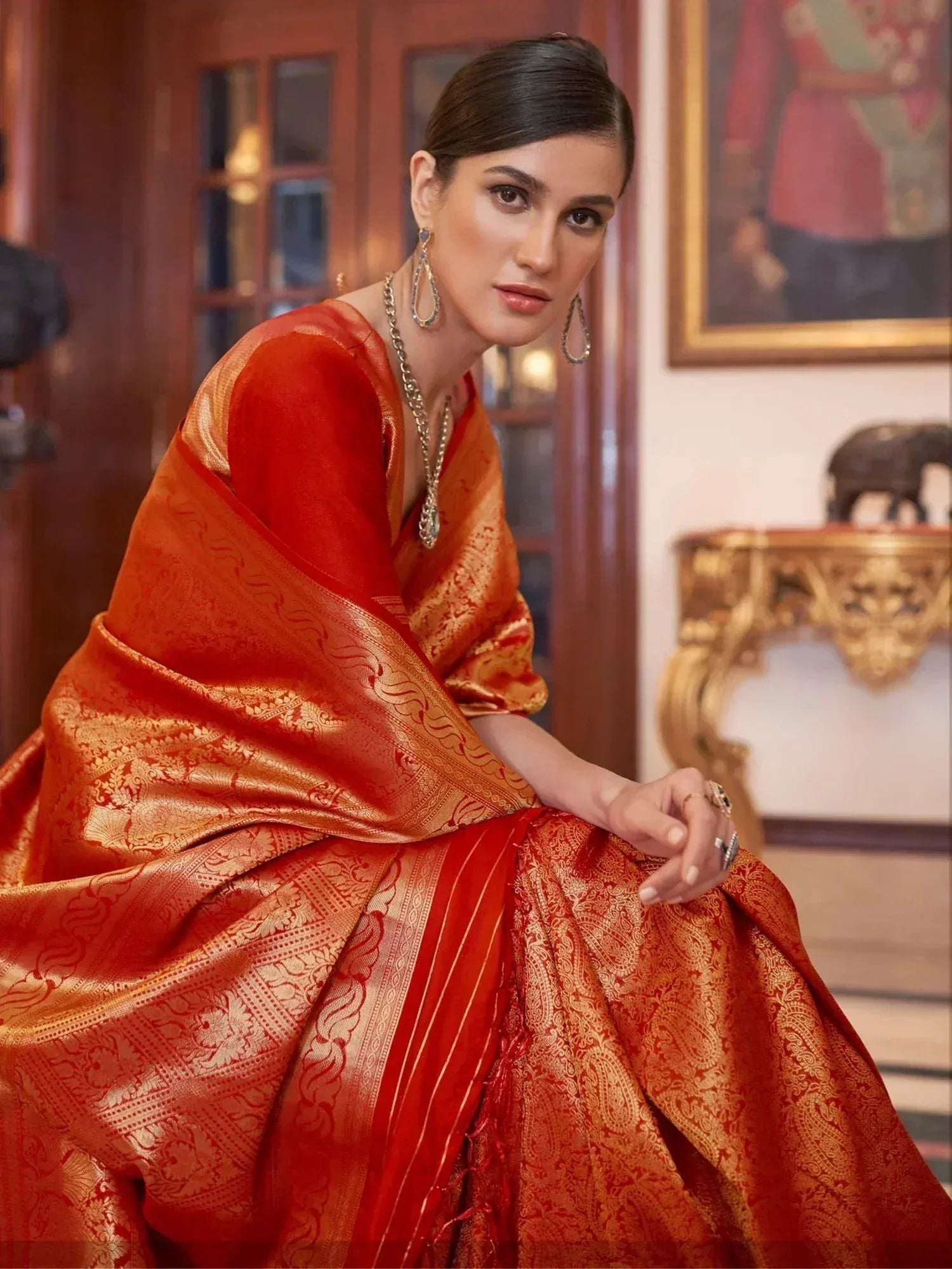 Elegant woman in red and gold designer saree with intricate embroidery, perfect for Indian ethnic wear occasions.