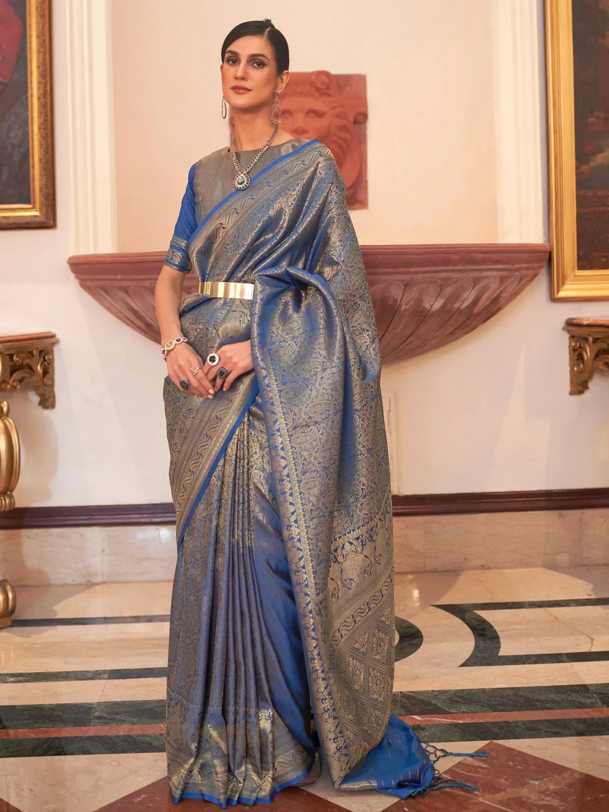 Blue and gold designer saree with intricate paisley patterns, paired with statement jewelry for ethnic wear.