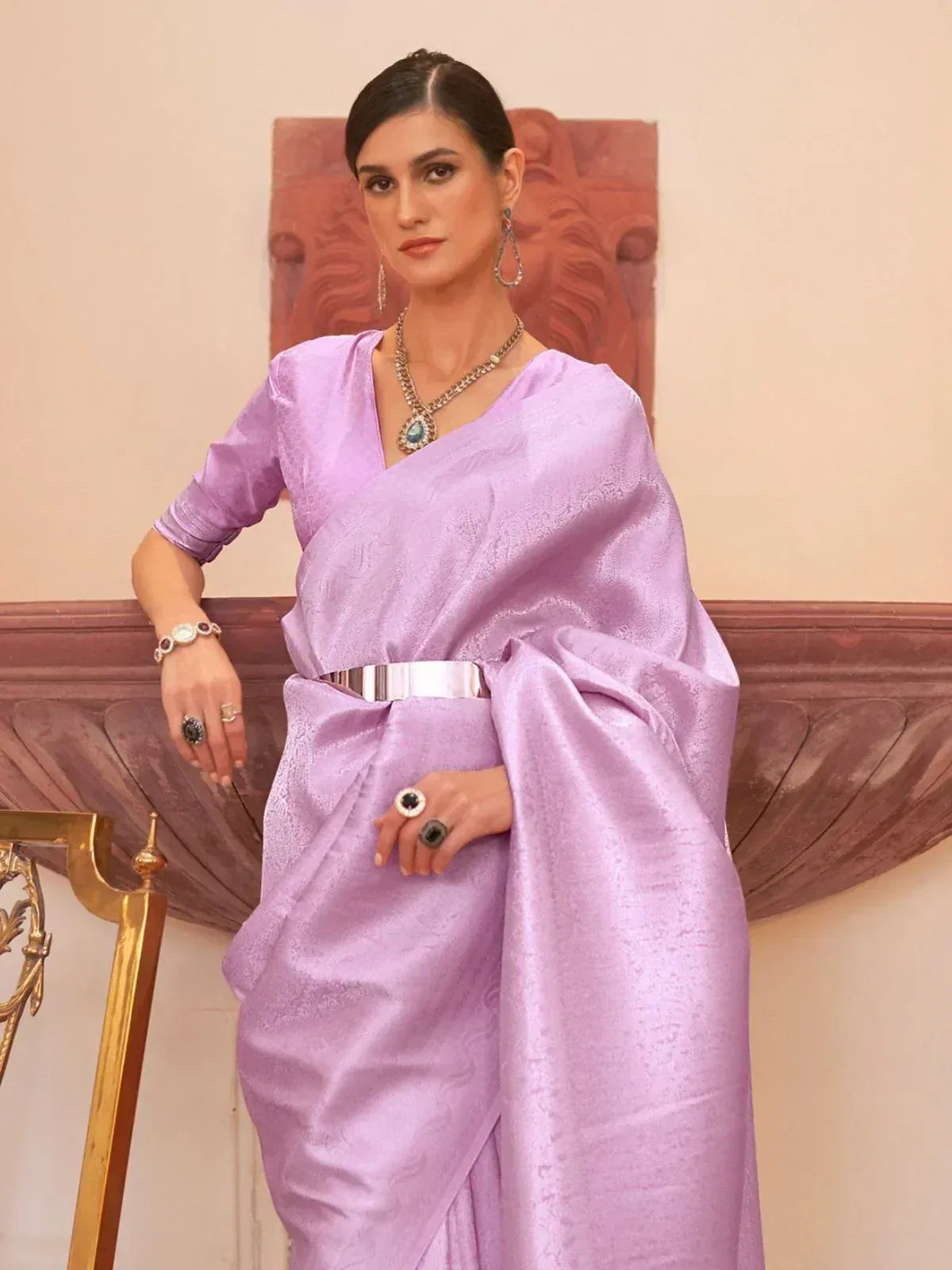 Lavender designer saree with V-neck blouse, silver belt, and statement jewelry for ethnic occasions