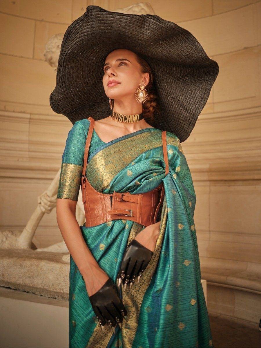 Teal designer saree with gold motifs, wide-brim hat, and leather belt for ethnic fashion