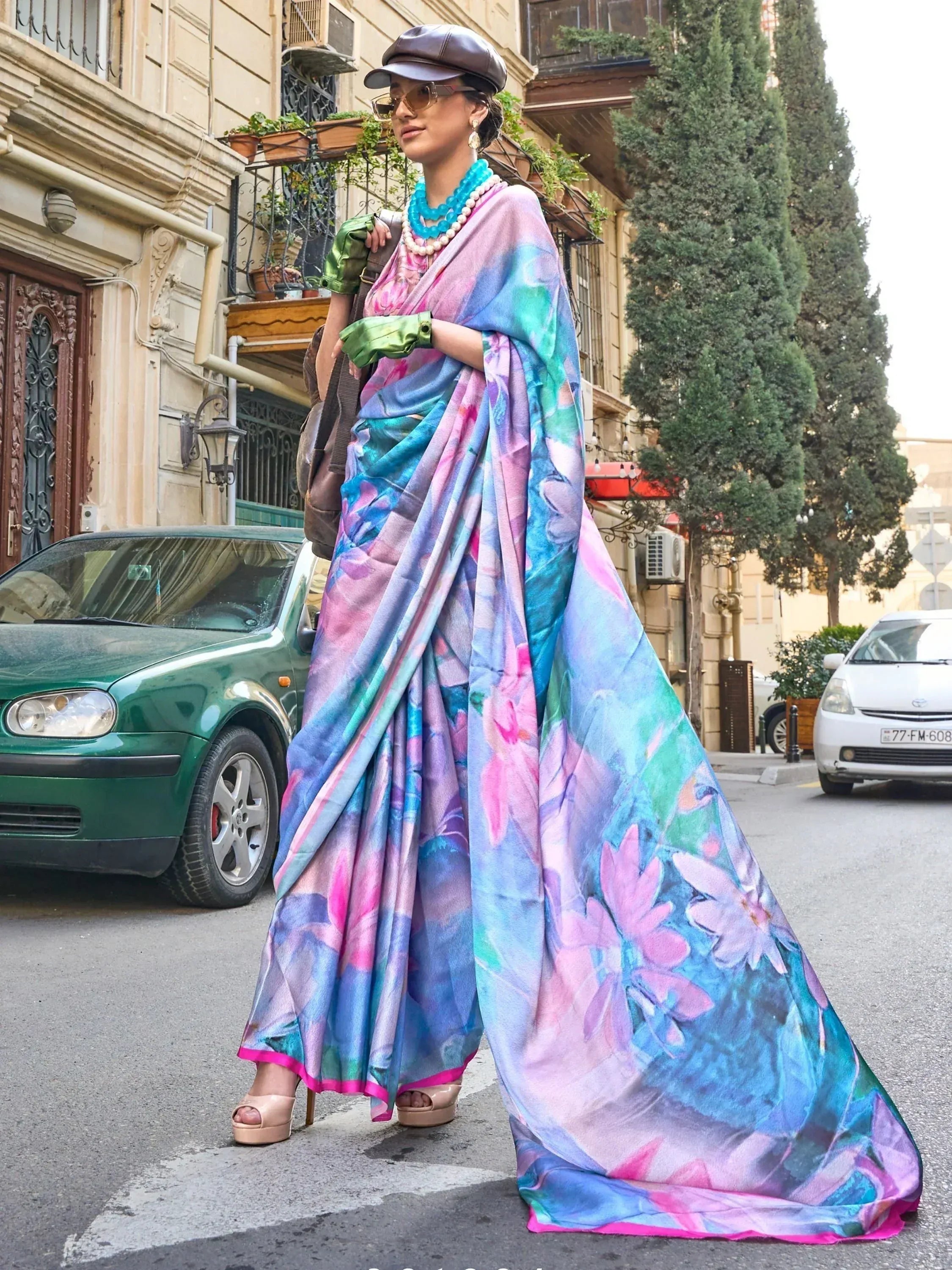 Woman in vibrant floral saree with pastel hues, styled with cap and gloves for street fashion