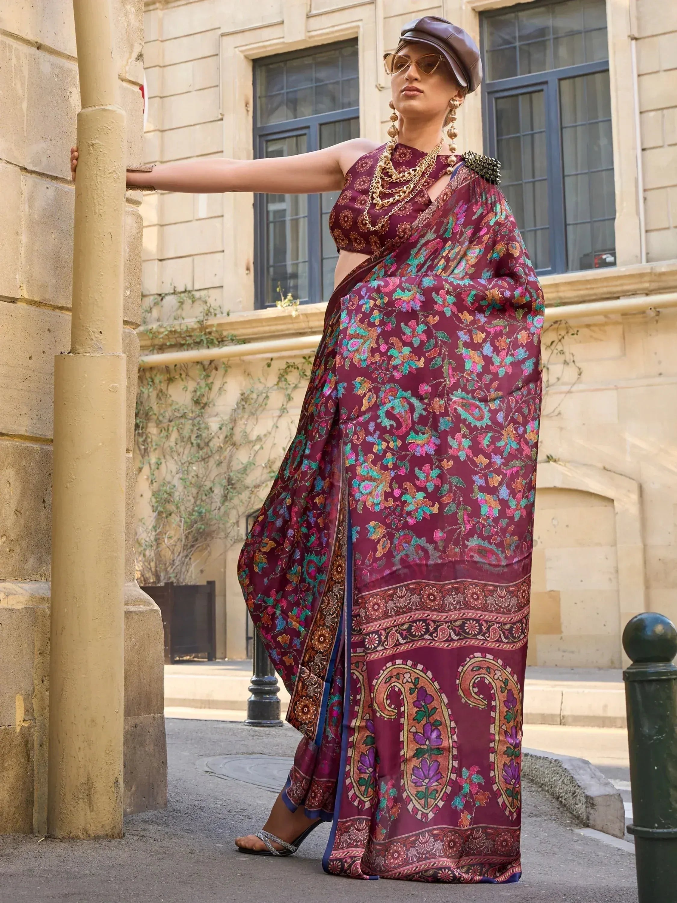 Woman in maroon floral saree with gold jewelry and cap, styled for ethnic fashion