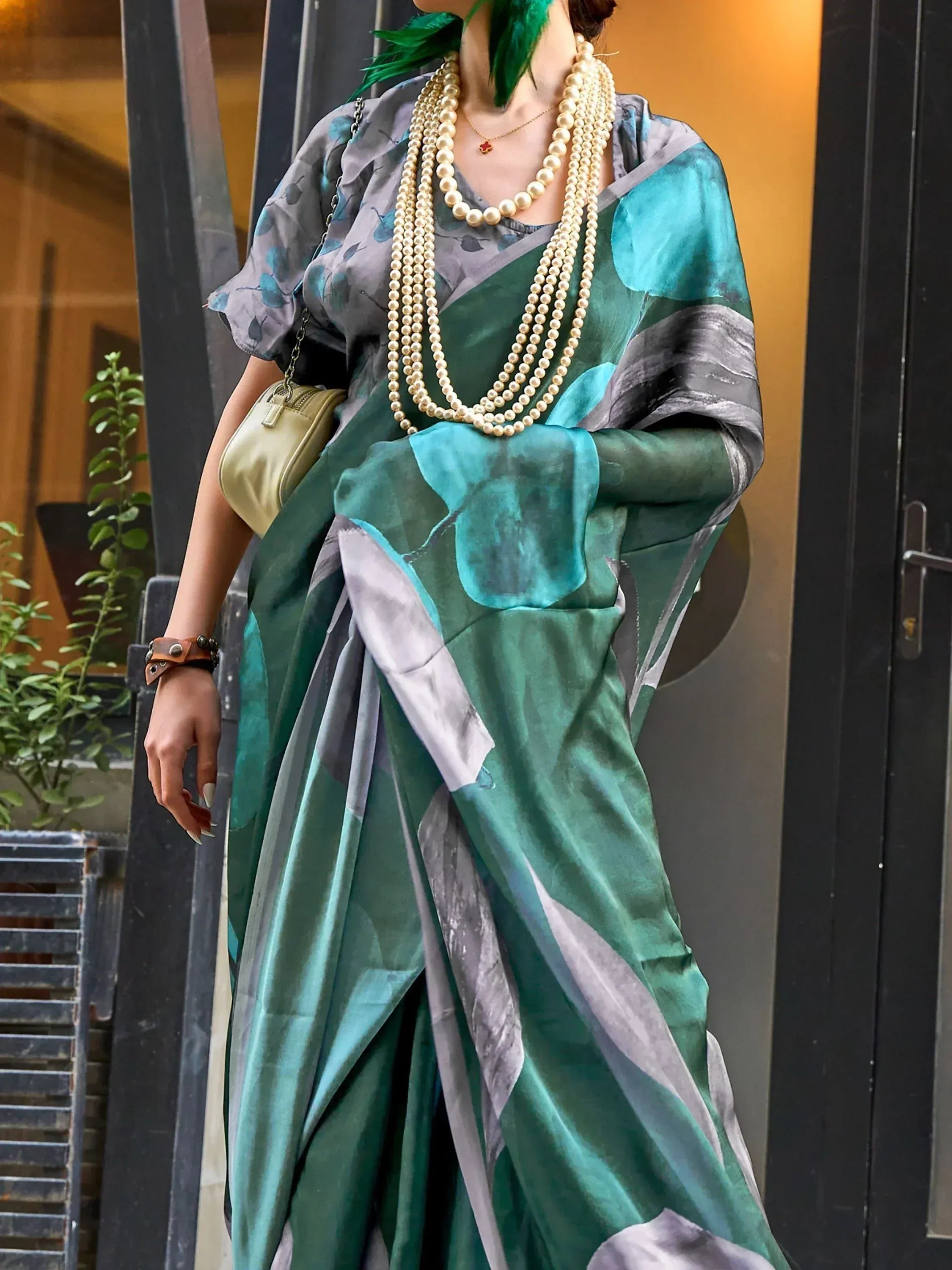 Stylish green and grey printed saree with pearl necklace, perfect for ethnic wear occasions.