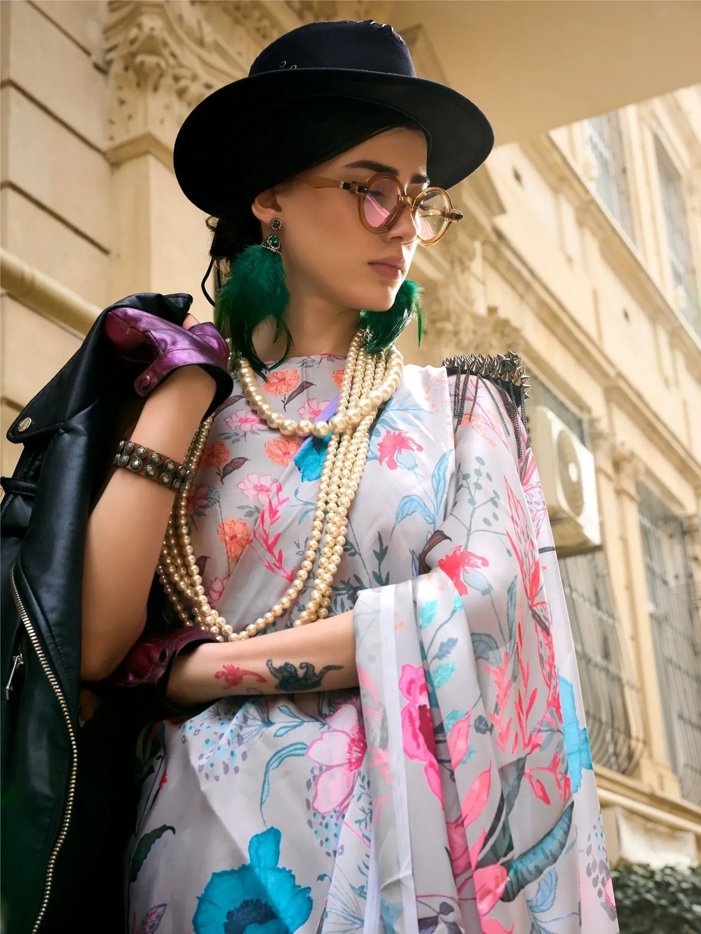 Floral print ethnic gown with pearl necklace, black hat, and green feather earrings for stylish Indian wear