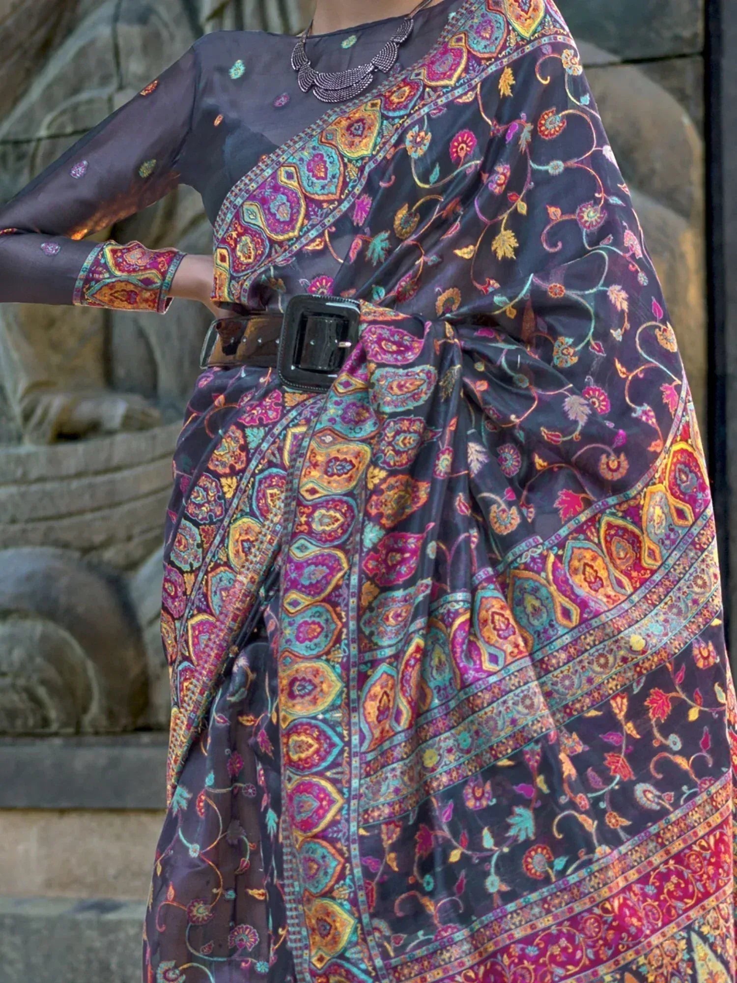 Black floral printed saree with vibrant paisley border, styled with belt and ethnic blouse