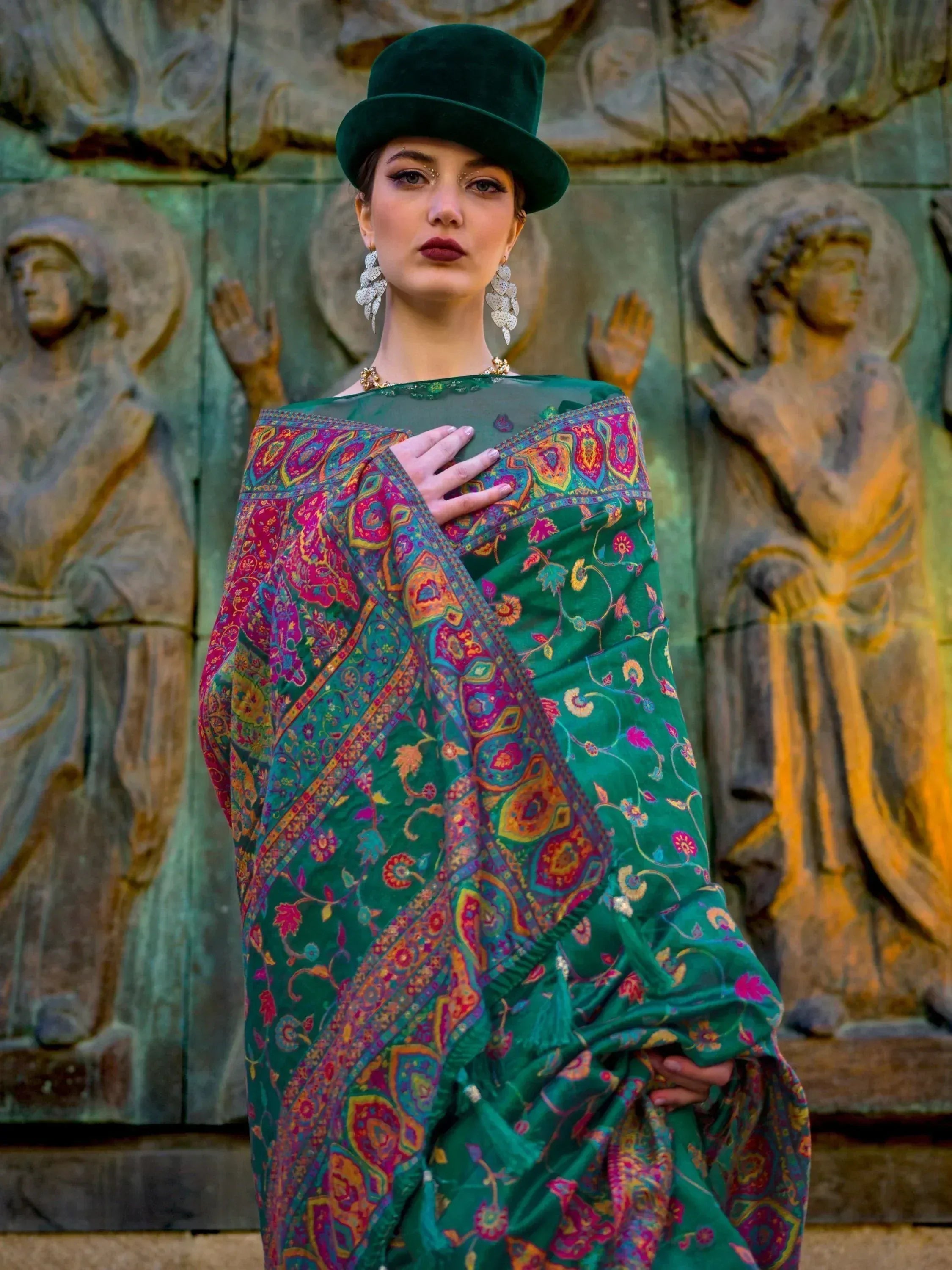 Green floral saree with paisley border, styled with velvet hat and statement earrings for ethnic wear