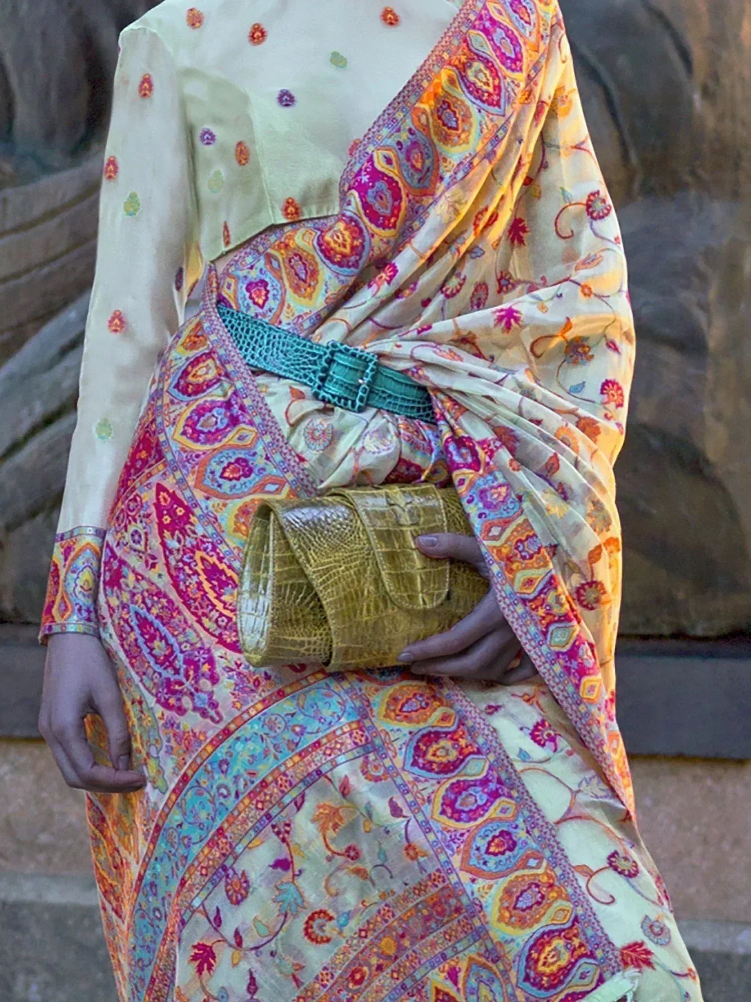 Colorful printed ethnic saree with turquoise belt and gold clutch, perfect for Indian occasions