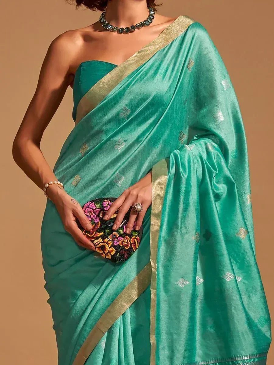 Teal silk saree with gold border and floral clutch, perfect for Indian ethnic wear occasions