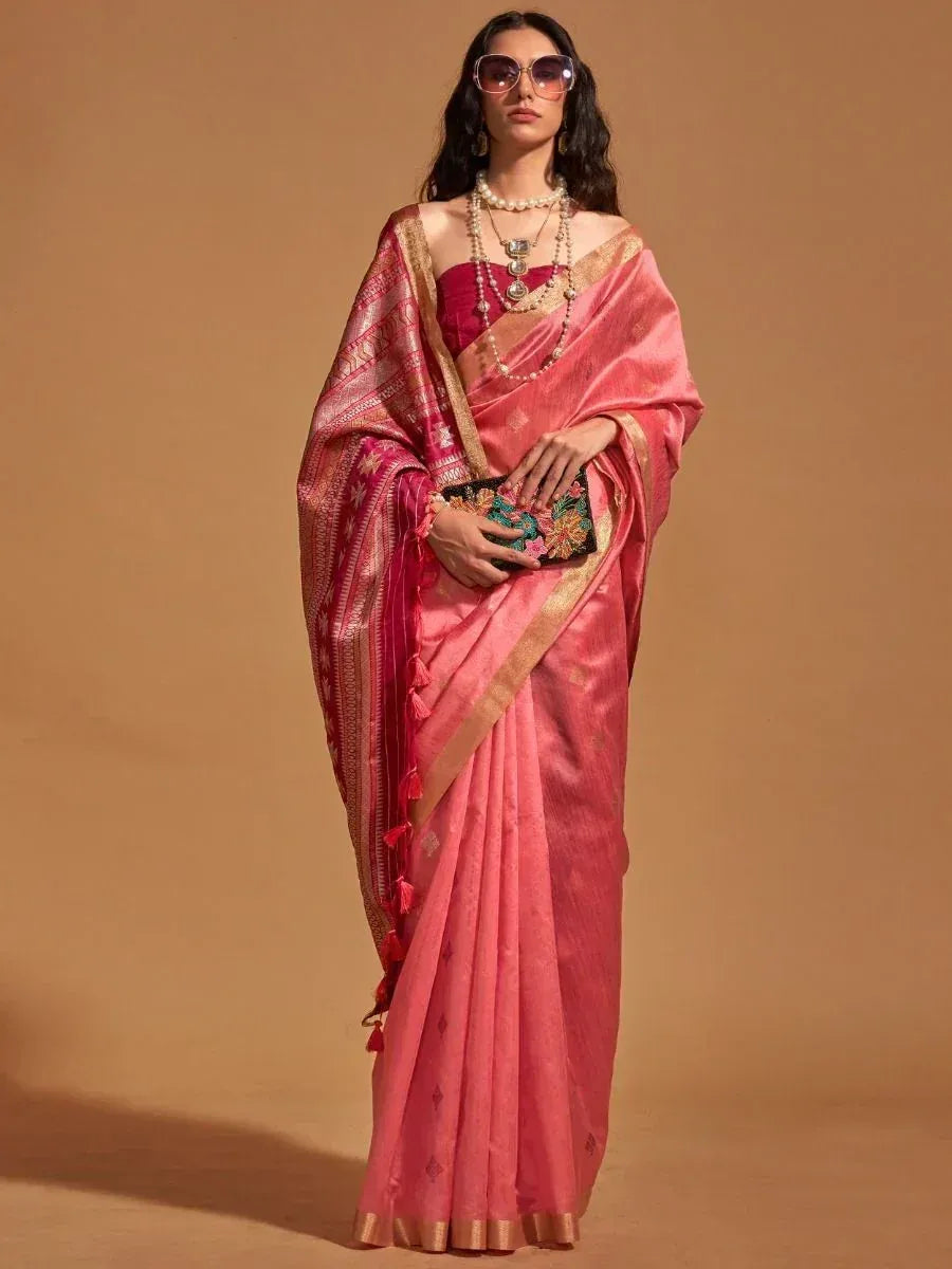 Elegant pink saree with gold border and tassels, paired with a red blouse and floral clutch