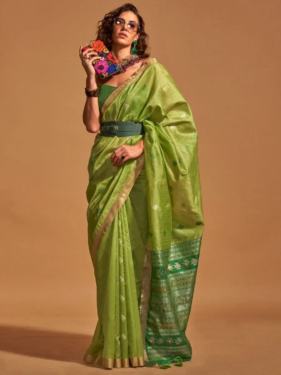 Green designer saree with gold border and belt, styled with floral clutch for ethnic wear