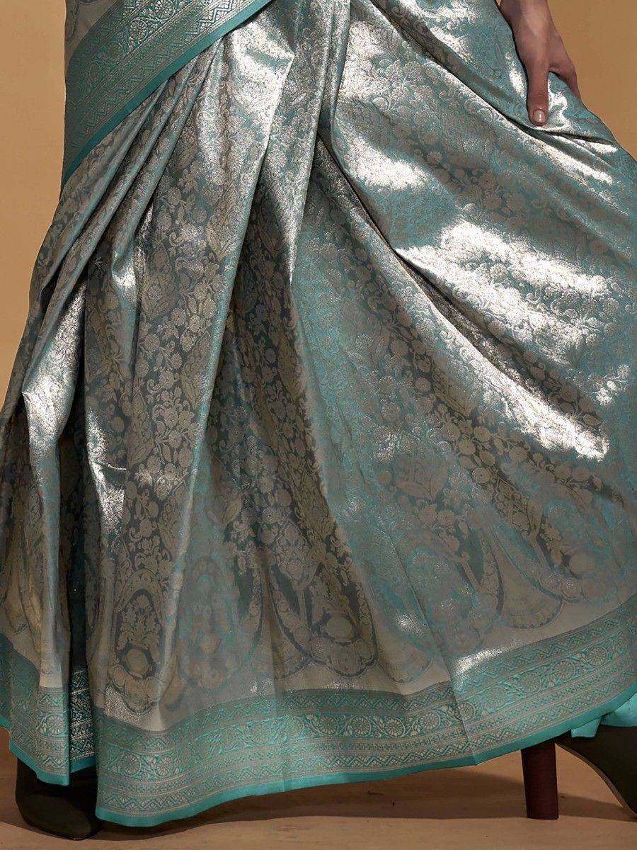 Teal and silver brocade saree with intricate floral patterns and detailed border, perfect for ethnic occasions