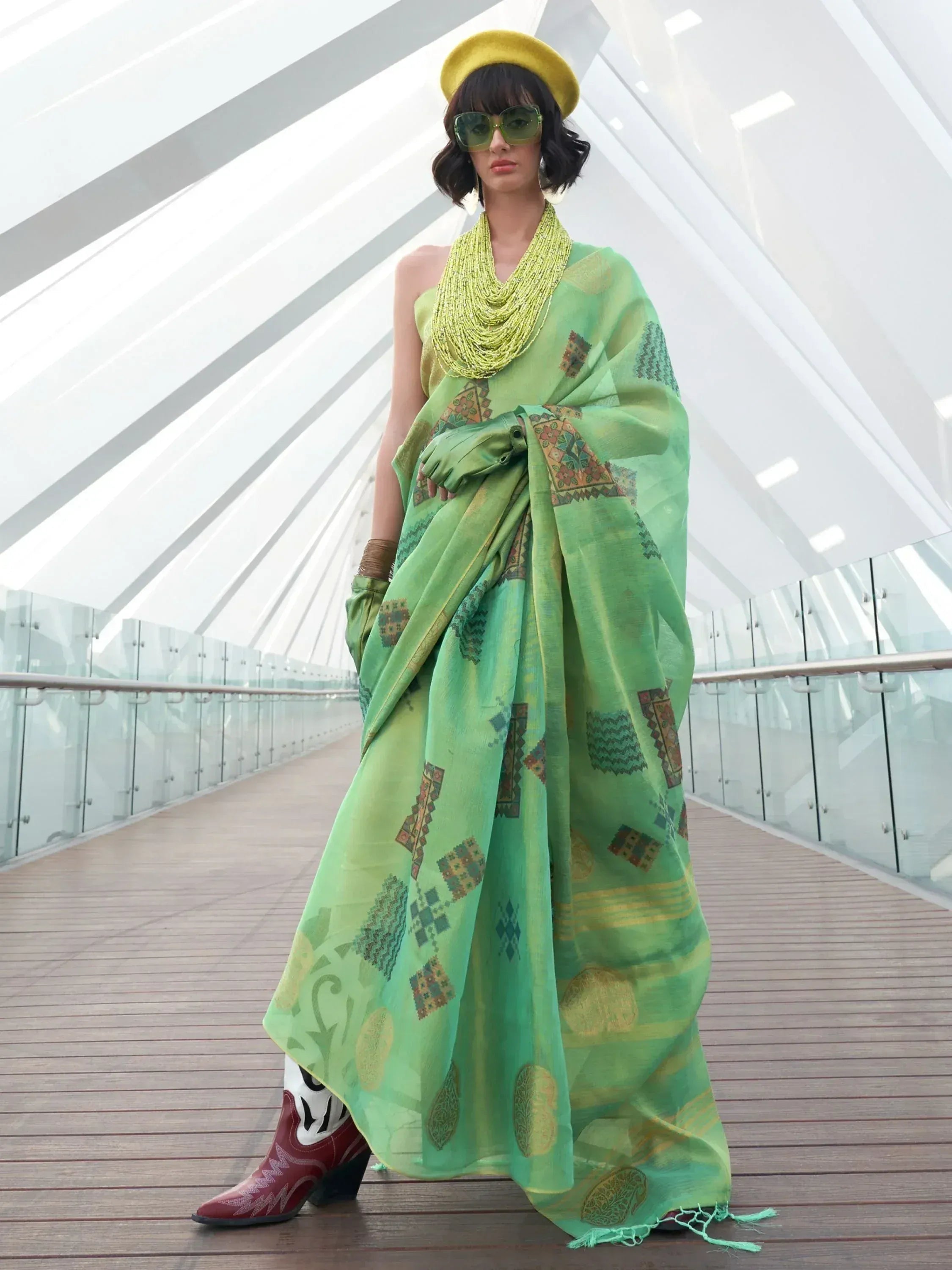 Stylish green printed saree with yellow beret and cowboy boots, modern ethnic wear