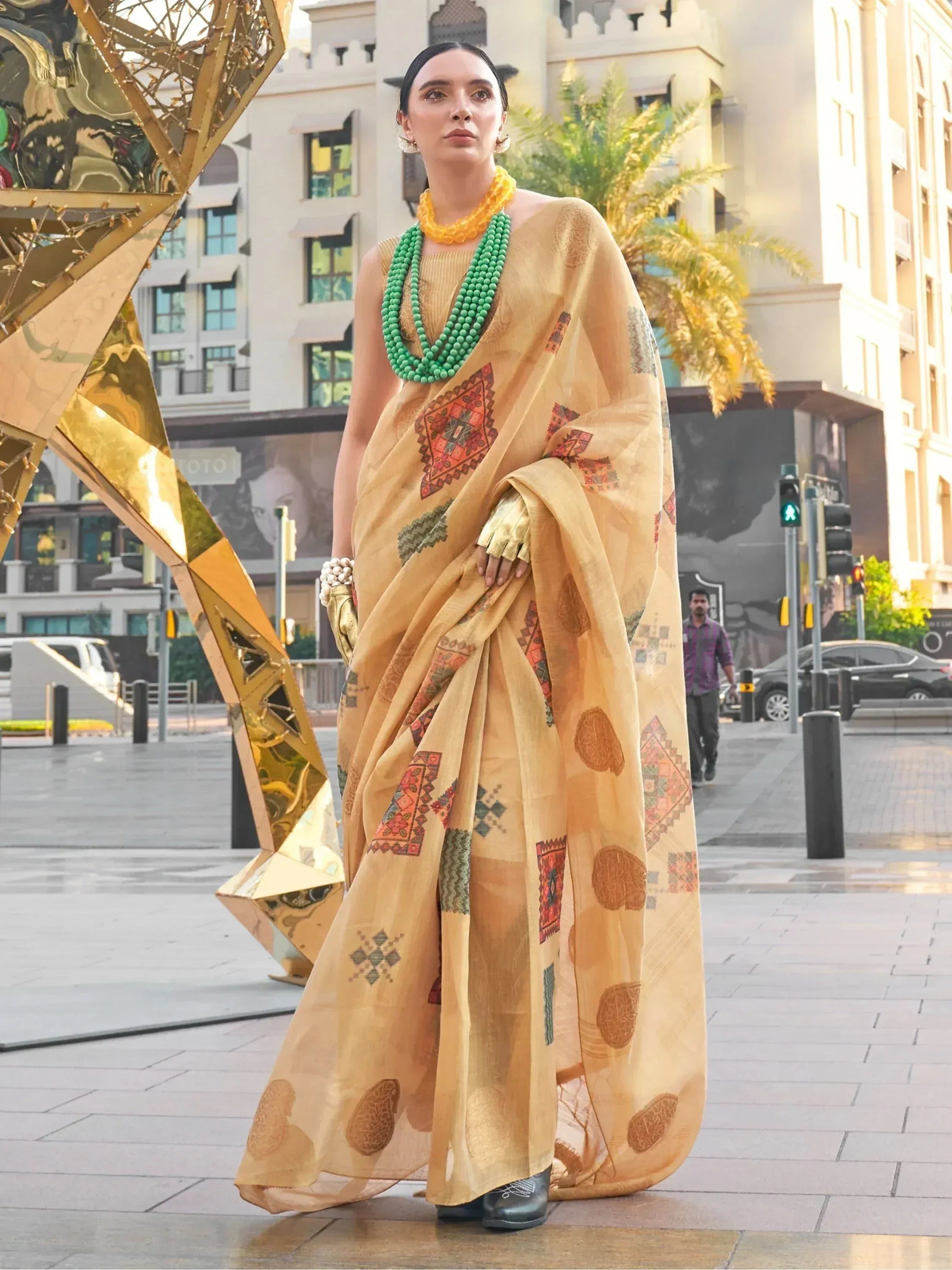Woman in mustard yellow printed saree with green beads, ethnic Indian wear for festive occasions