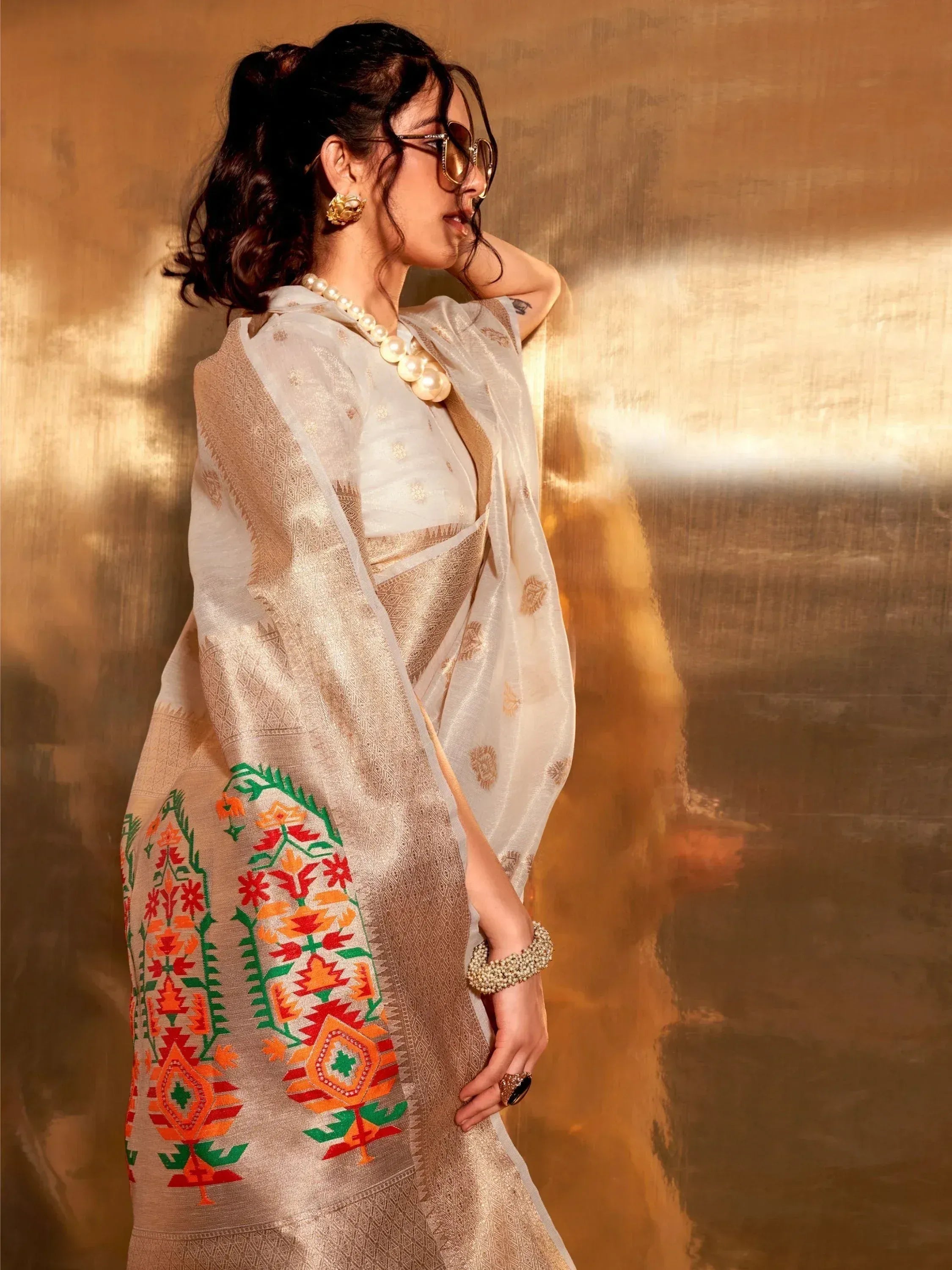 Elegant white saree with colorful floral embroidery, gold border, and pearl jewelry for Indian ethnic wear