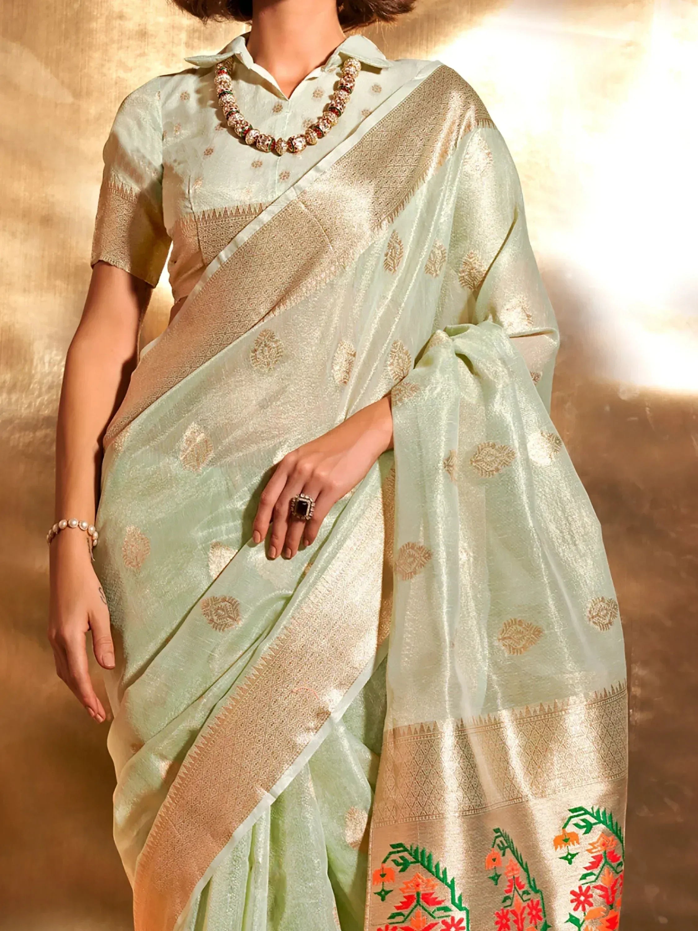 Elegant mint green saree with gold embroidery and floral border, paired with a matching blouse.