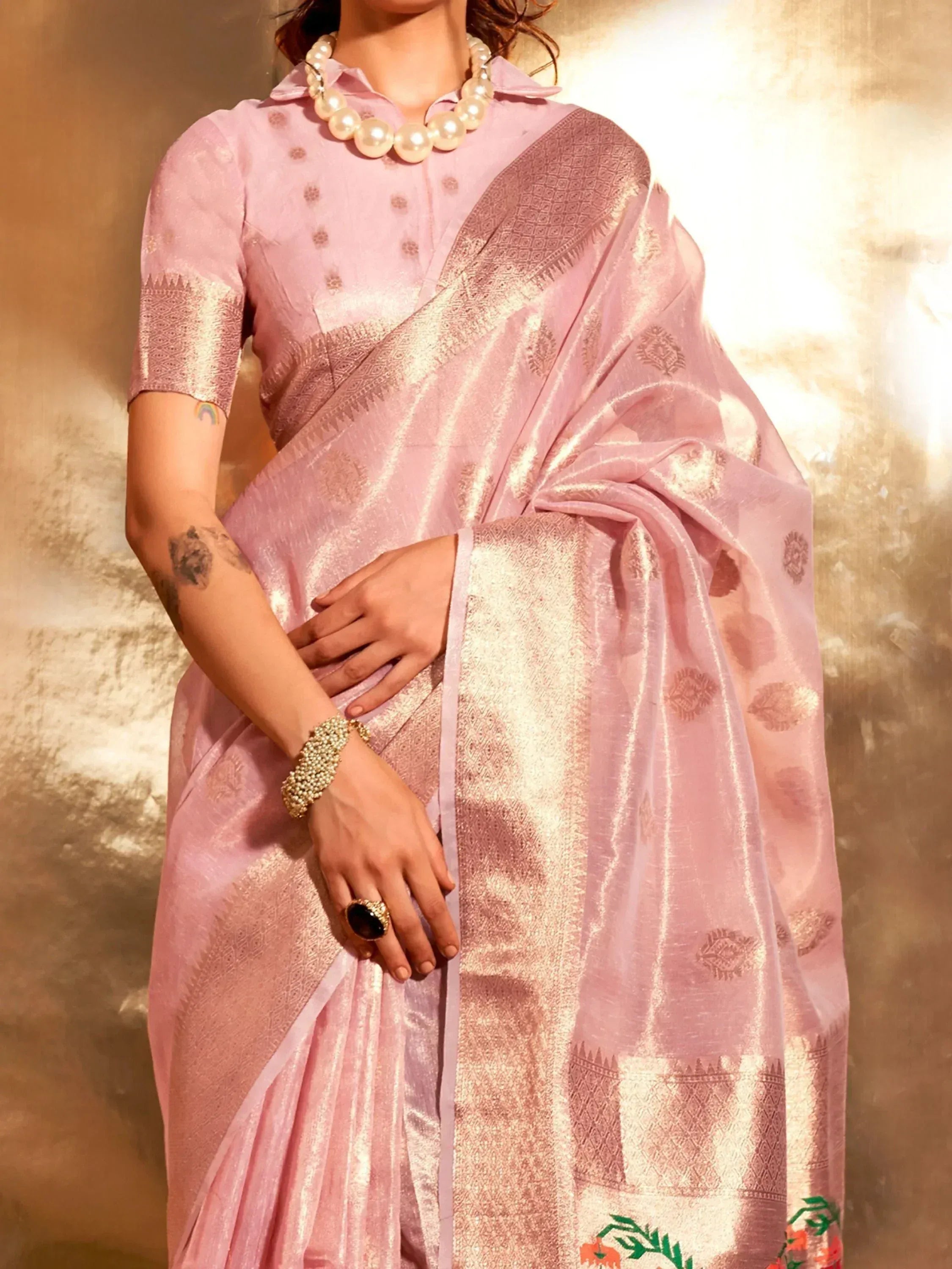 Pink designer saree with gold zari work, paired with pearl necklace and ethnic blouse for festive occasions