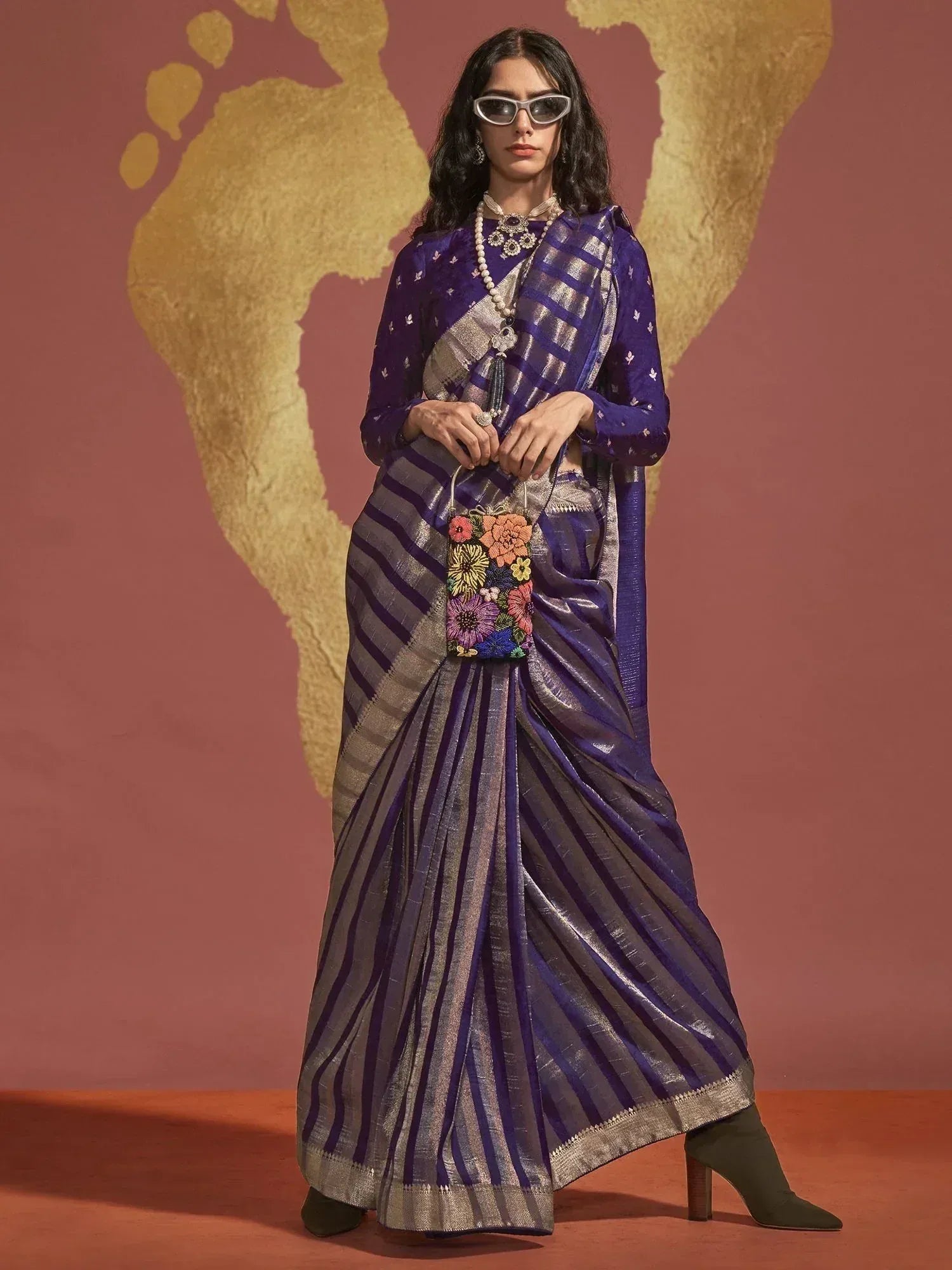 Purple and silver striped saree with floral potli bag, styled with sunglasses and statement jewelry