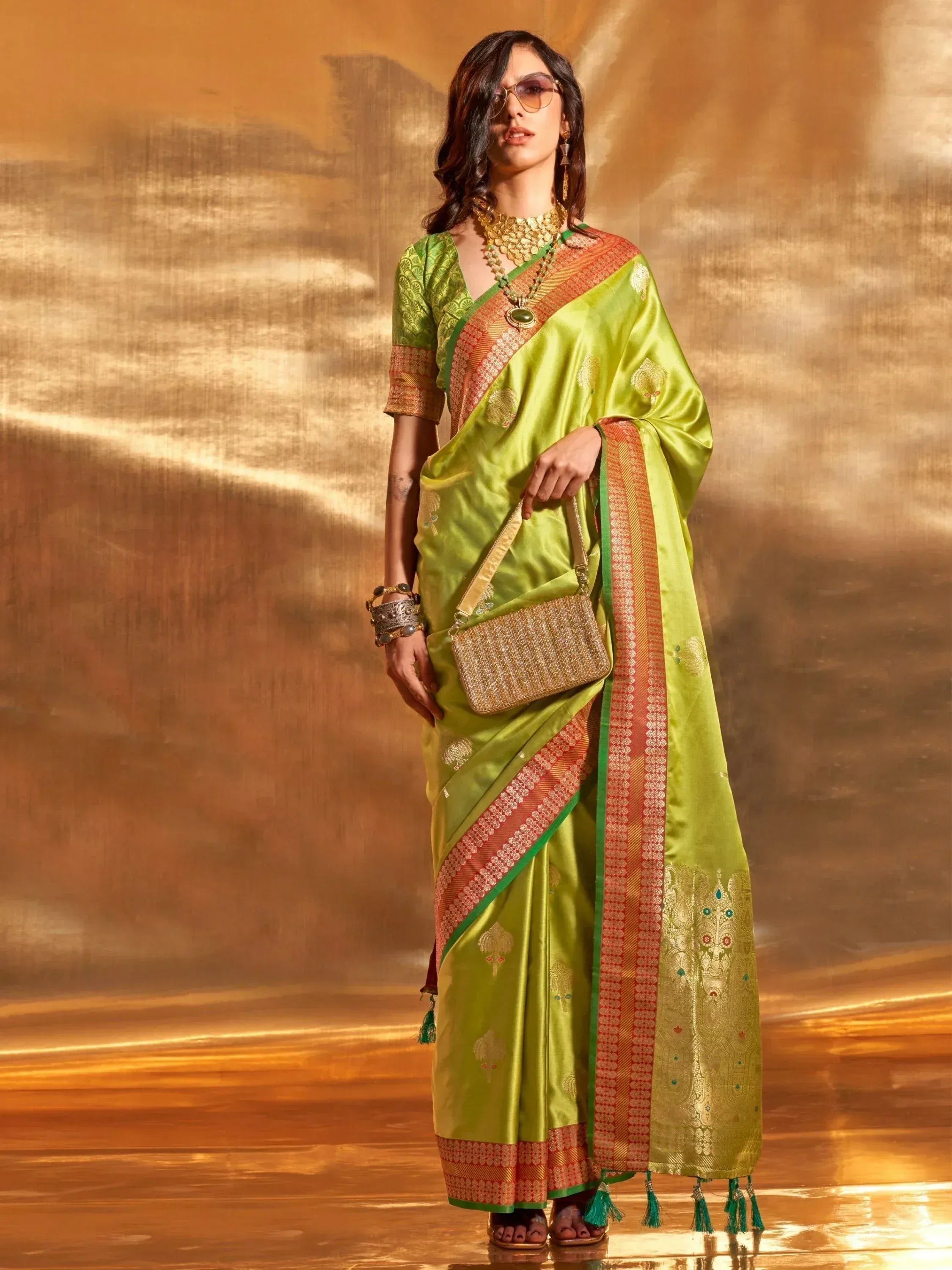 Lime green designer saree with gold embroidery and orange border, paired with matching blouse and jewelry
