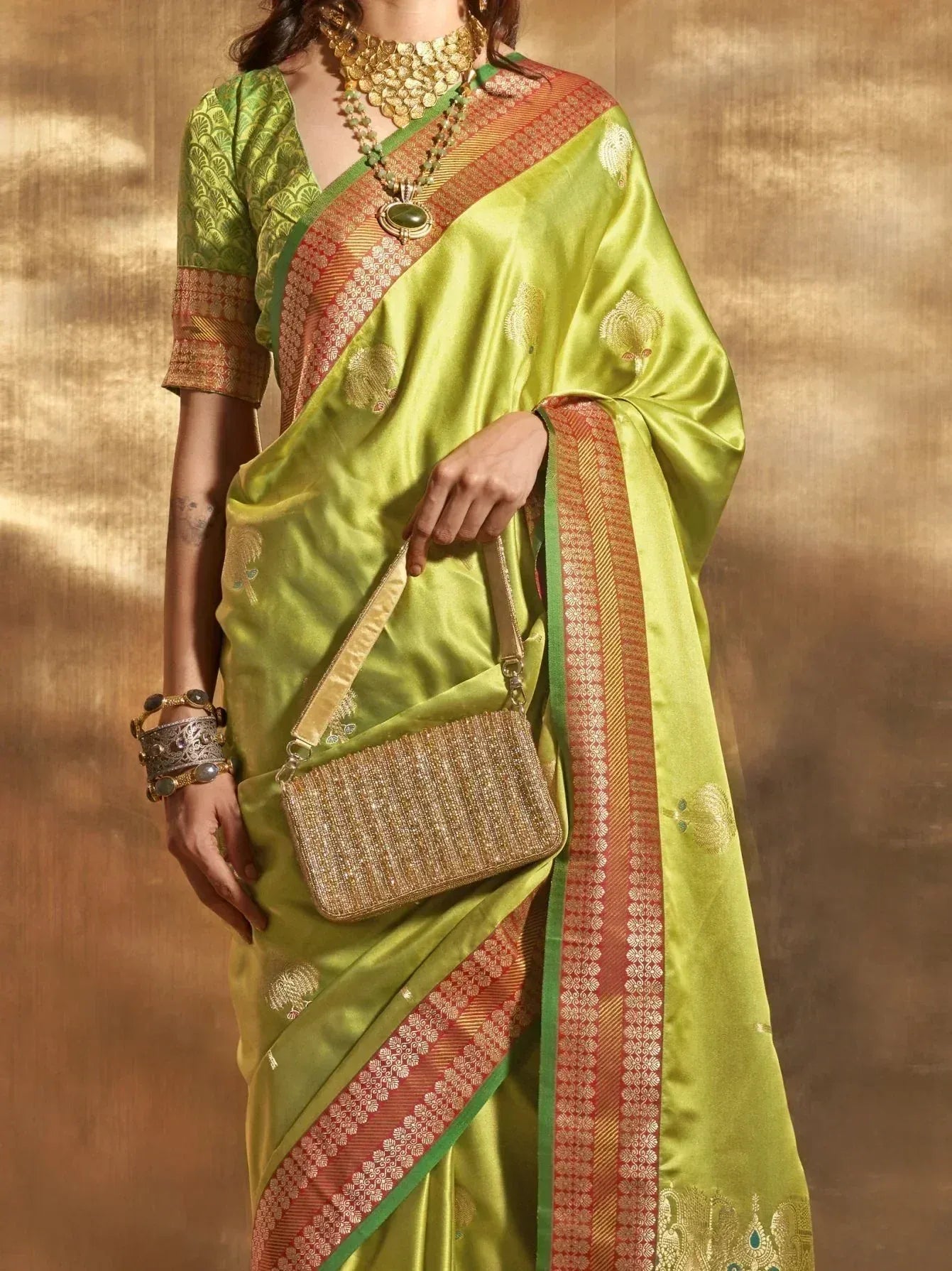 Lime green designer saree with gold embroidery and red border, paired with matching blouse and ethnic jewelry