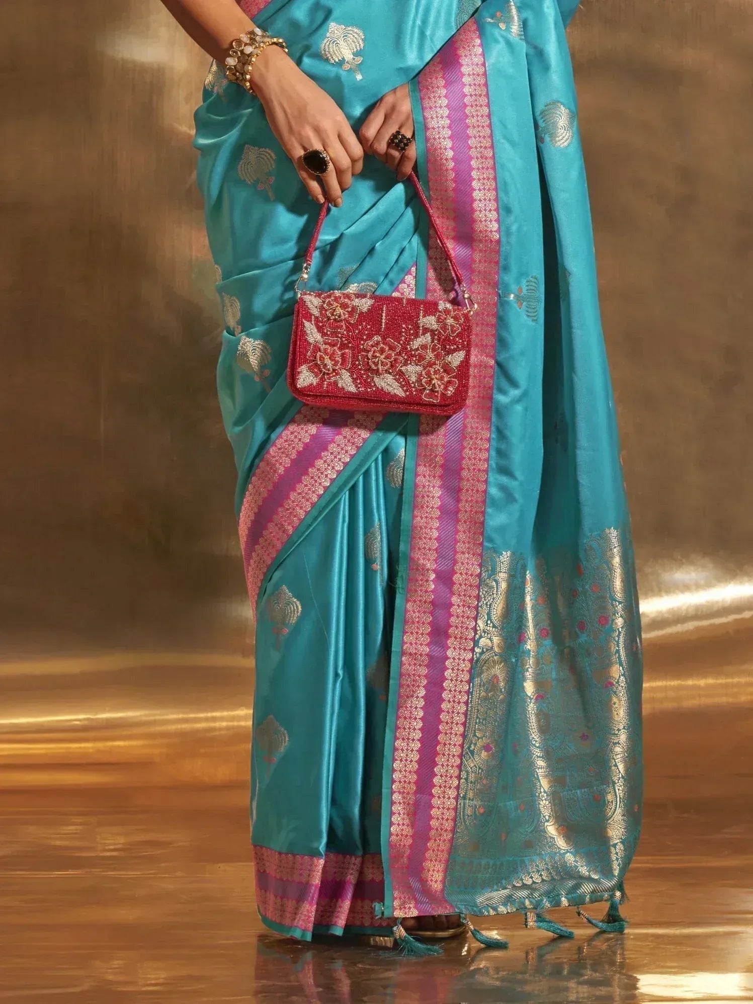 Turquoise silk saree with pink border, gold motifs, and matching embroidered clutch for Indian ethnic wear