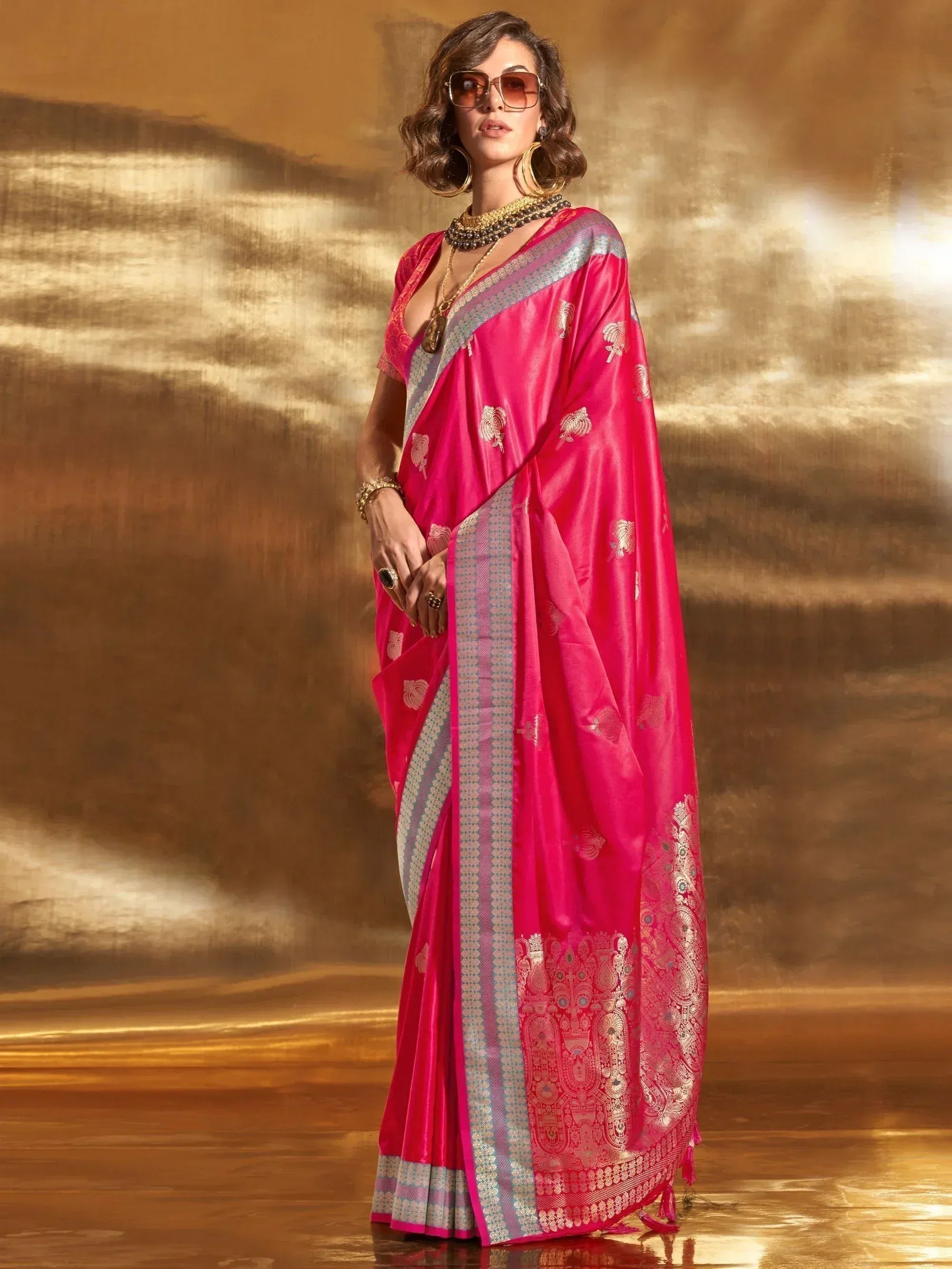 Vibrant pink silk saree with gold zari work and silver border, styled with statement jewelry for ethnic occasions