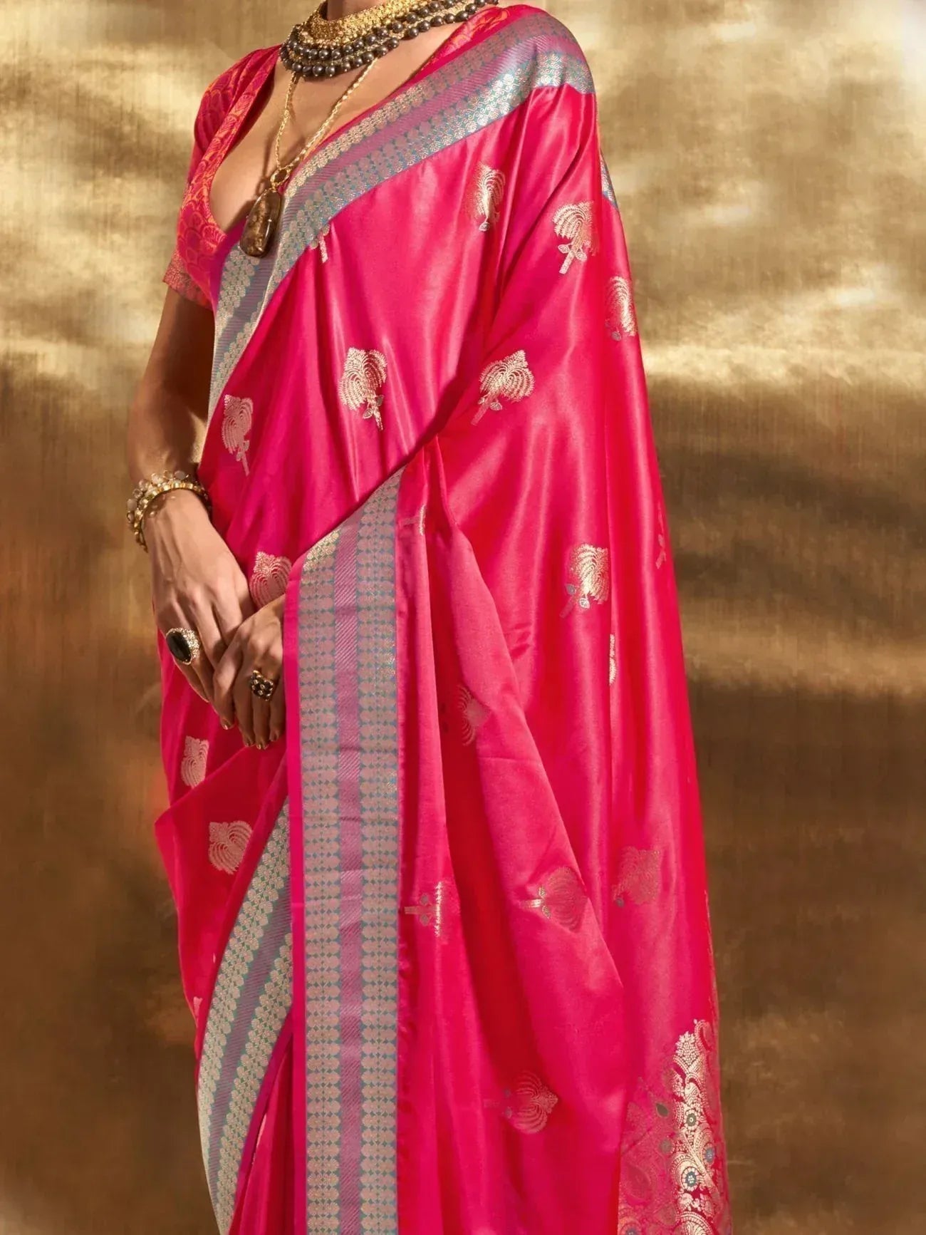 Vibrant pink silk saree with gold floral motifs and woven border, styled with traditional jewelry for ethnic occasions