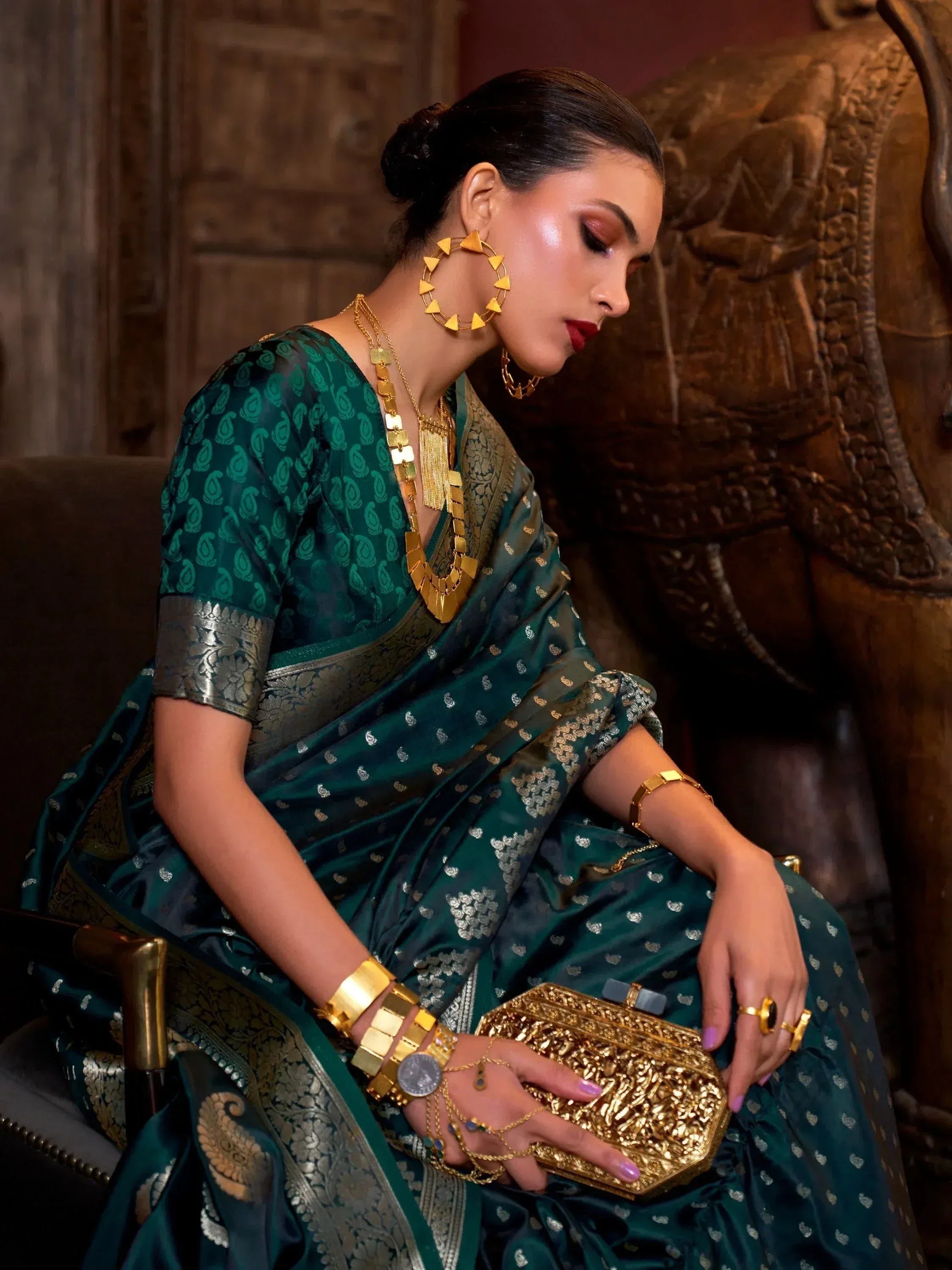 Elegant woman in green ethnic saree with gold jewelry and clutch, perfect for Indian occasions