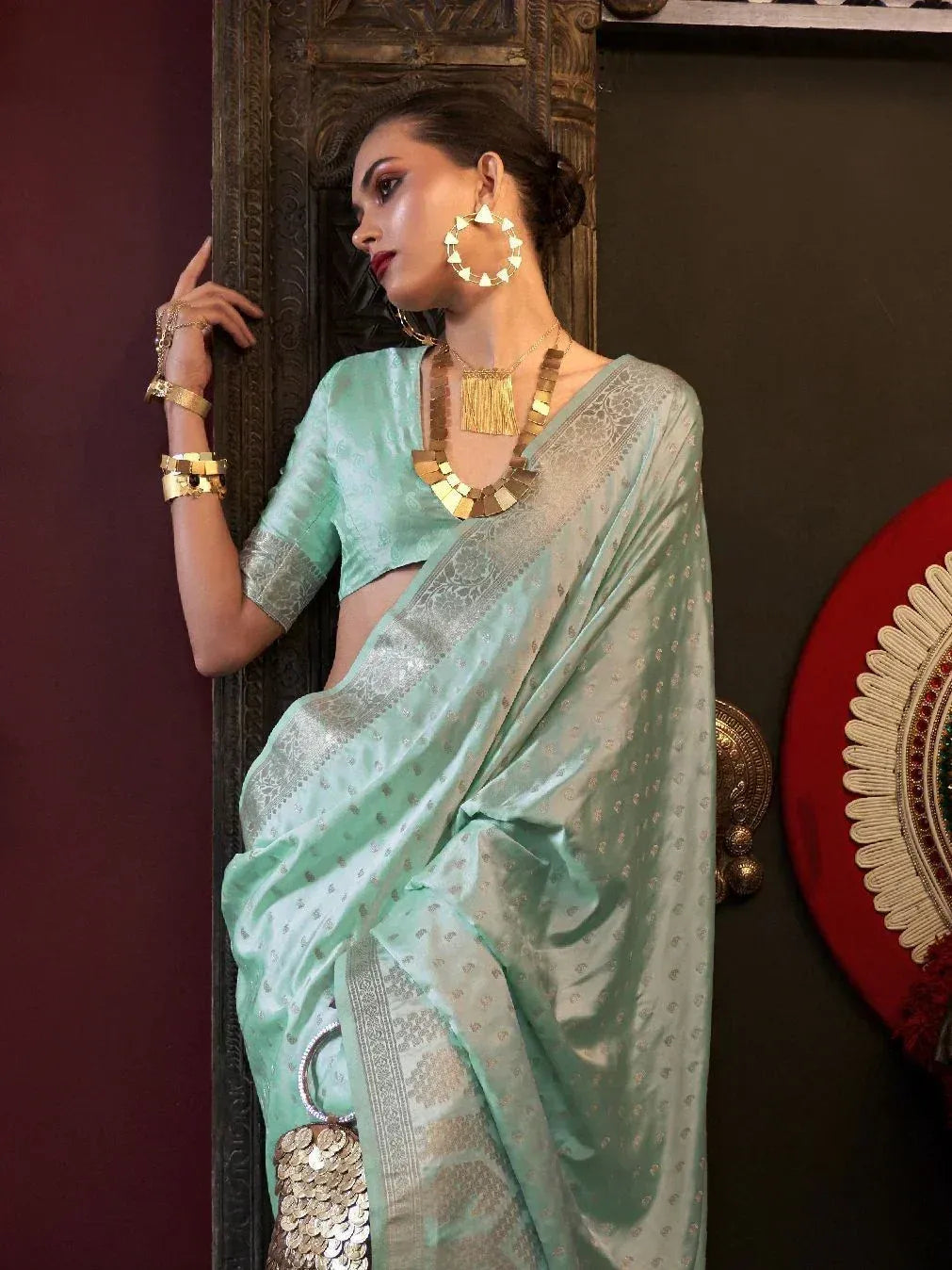 Mint green designer saree with silver zari work, paired with gold jewelry and statement earrings