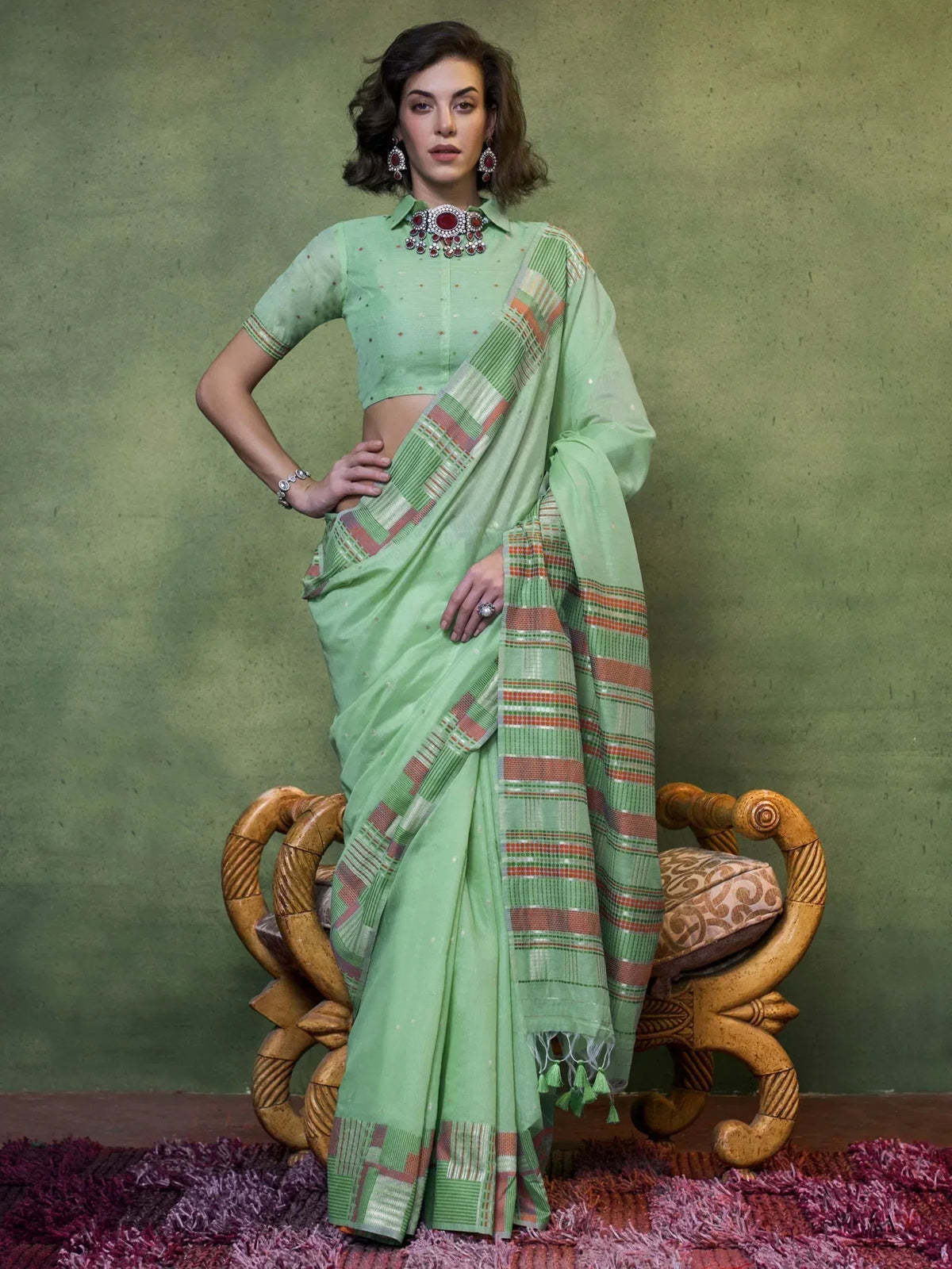 Mint green ethnic saree with geometric border, paired with matching blouse and statement jewelry