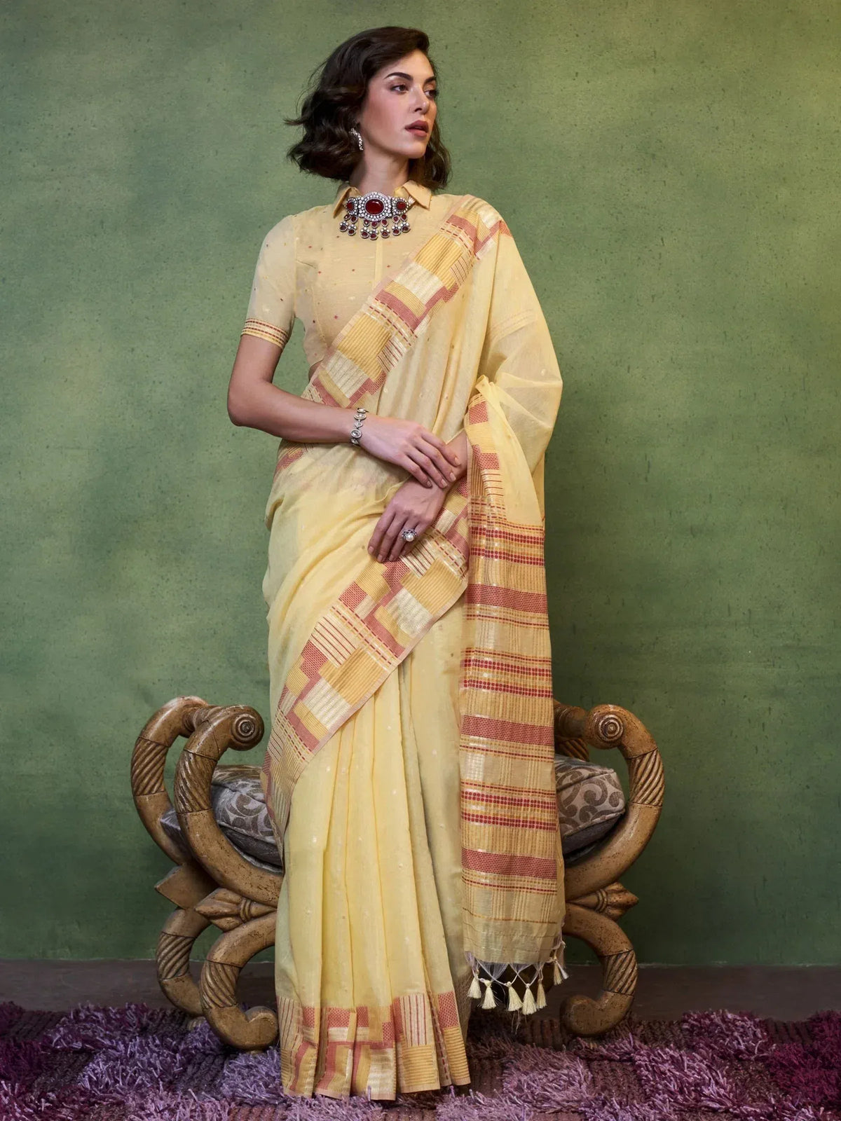 Yellow ethnic saree with red and gold checkered border, styled with statement necklace for Indian occasions