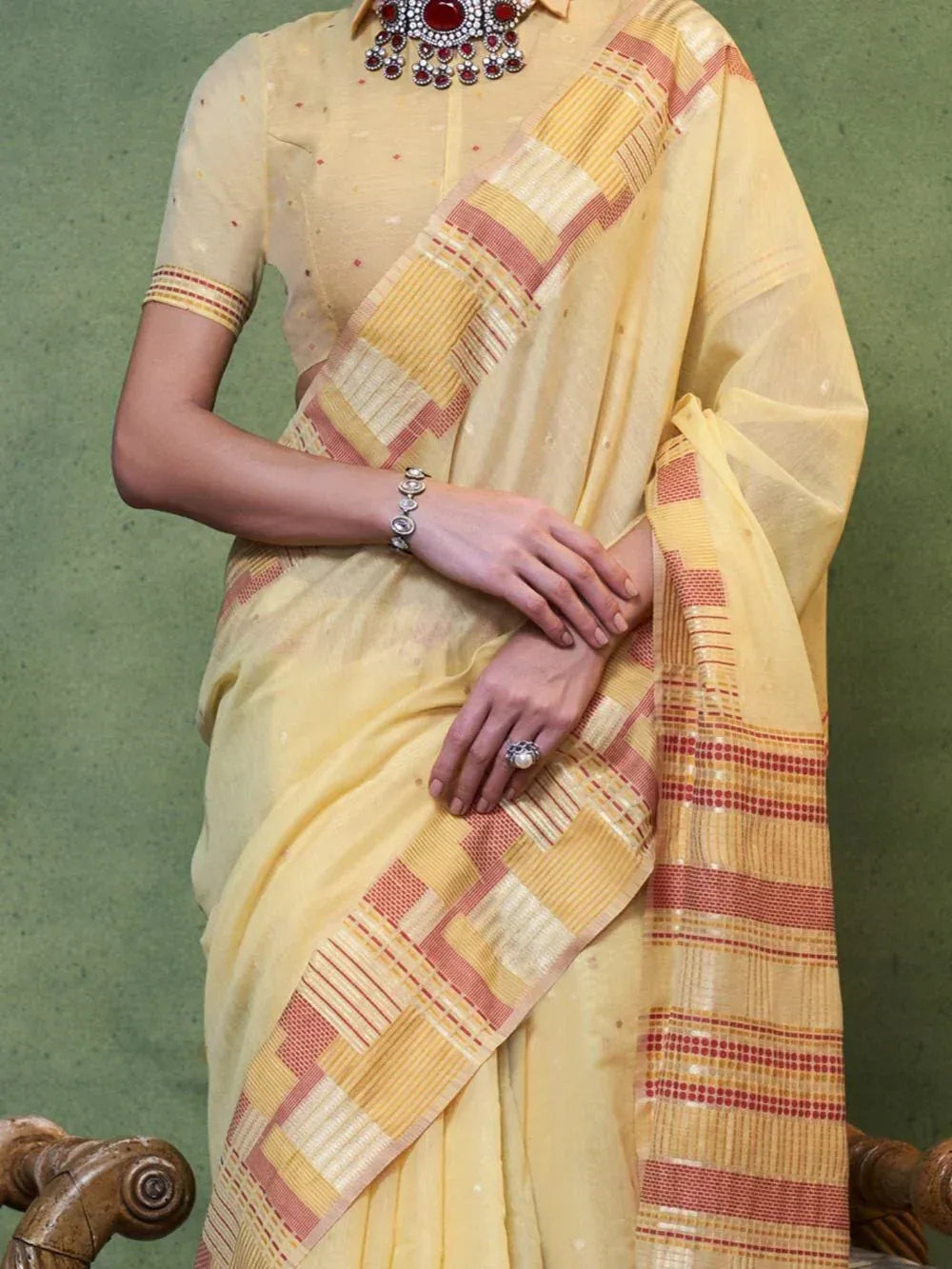 Yellow ethnic saree with red and gold geometric border, paired with matching blouse and statement jewelry