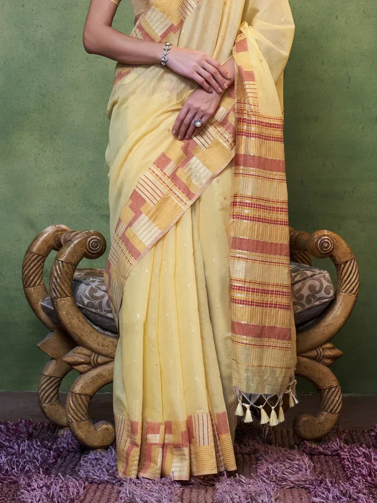 Yellow ethnic saree with red and gold checkered border, tassels, and woven texture, styled for traditional Indian wear