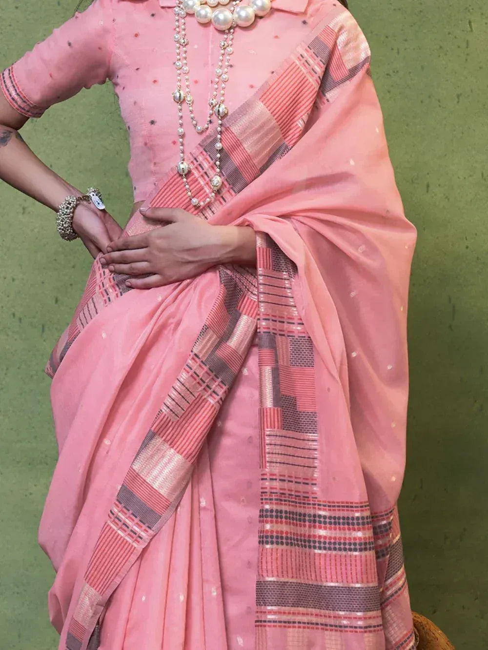 Pink ethnic saree with geometric border, paired with pearl jewelry and matching blouse
