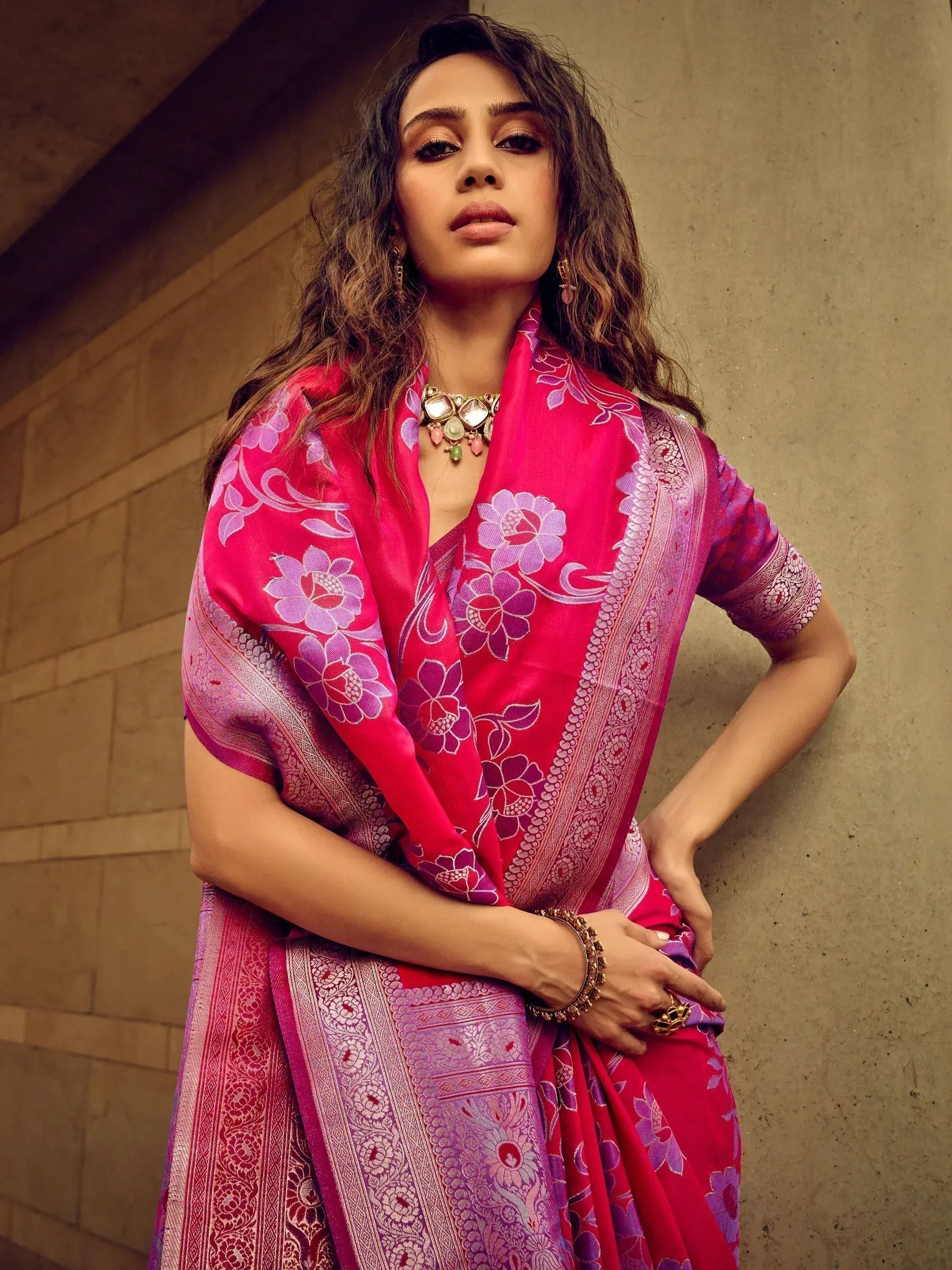 Woman in vibrant pink and purple floral saree with intricate border, styled for Indian ethnic wear