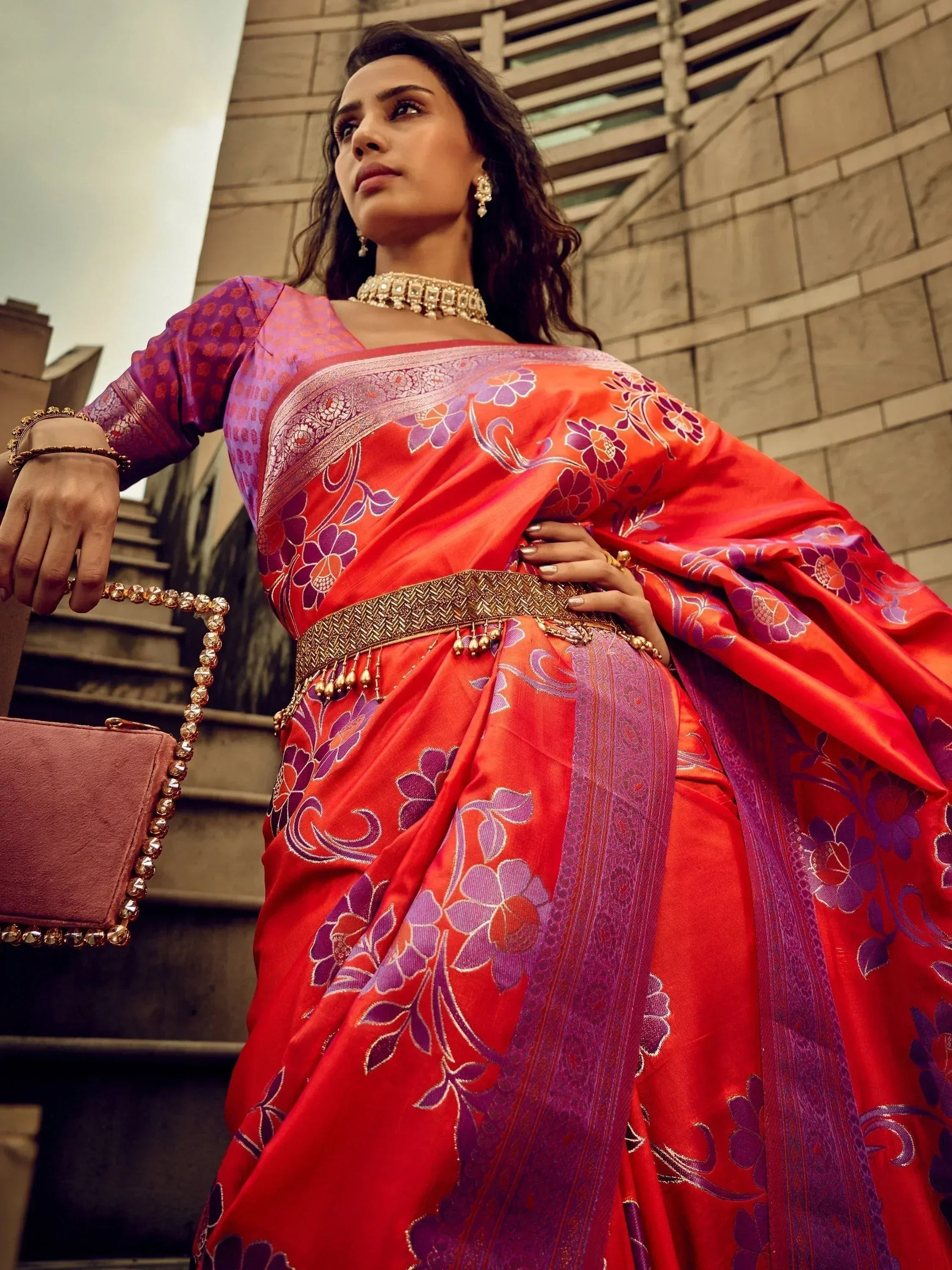 Woman in vibrant red and purple floral saree with gold belt, styled for ethnic occasions