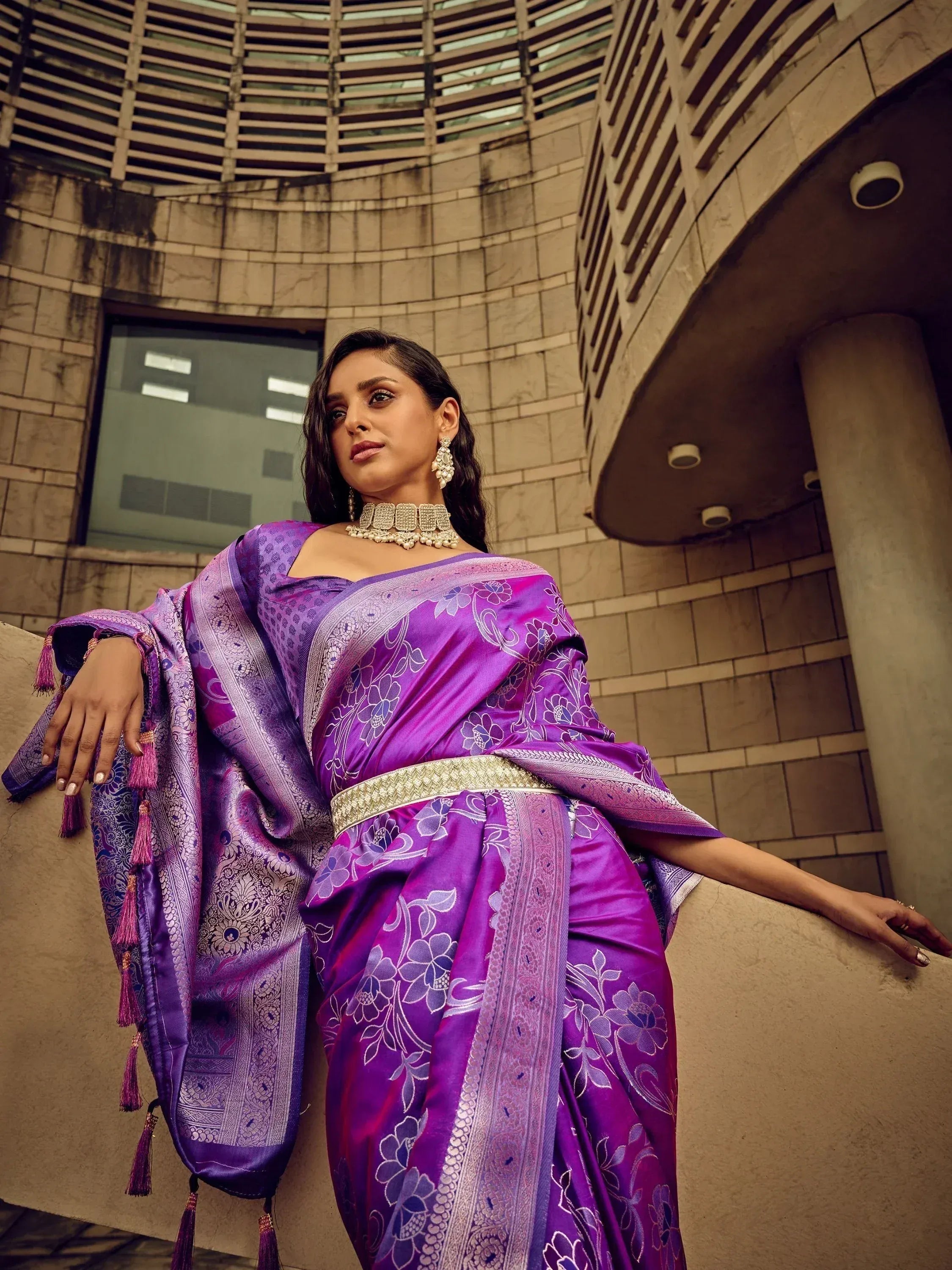 Purple floral designer saree with gold border and tassels, styled with traditional jewelry for ethnic wear