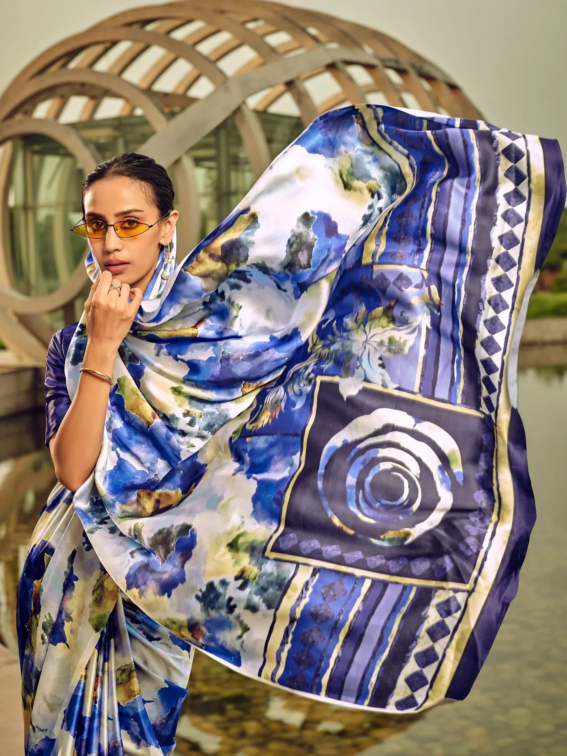 Woman in blue floral saree with artistic watercolor print, styled with sunglasses and elegant drape