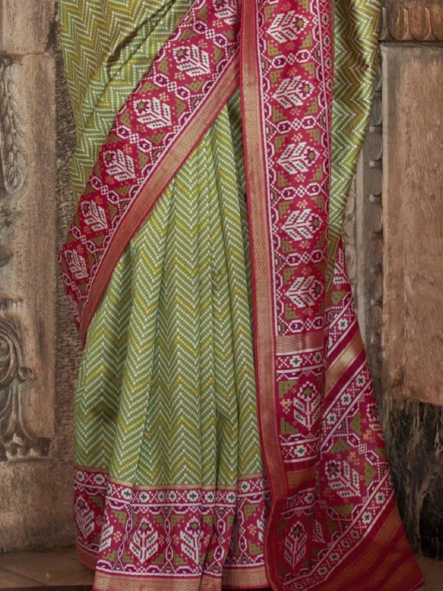 Green and red ethnic saree with geometric and floral motifs, perfect for traditional Indian occasions.